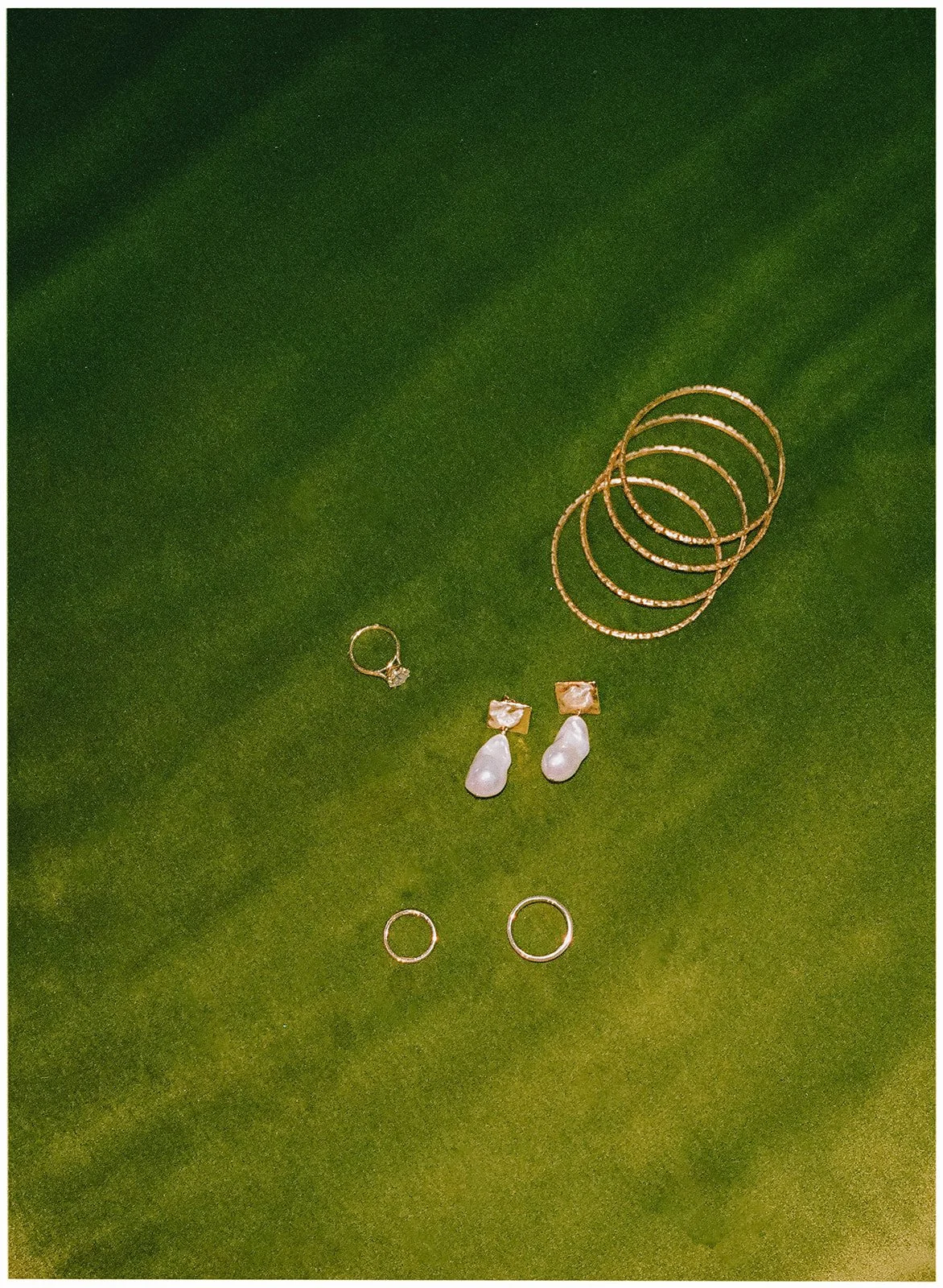 Collection of jewelry including several necklaces, earrings, rings, and bracelets displayed on a green fabric background.