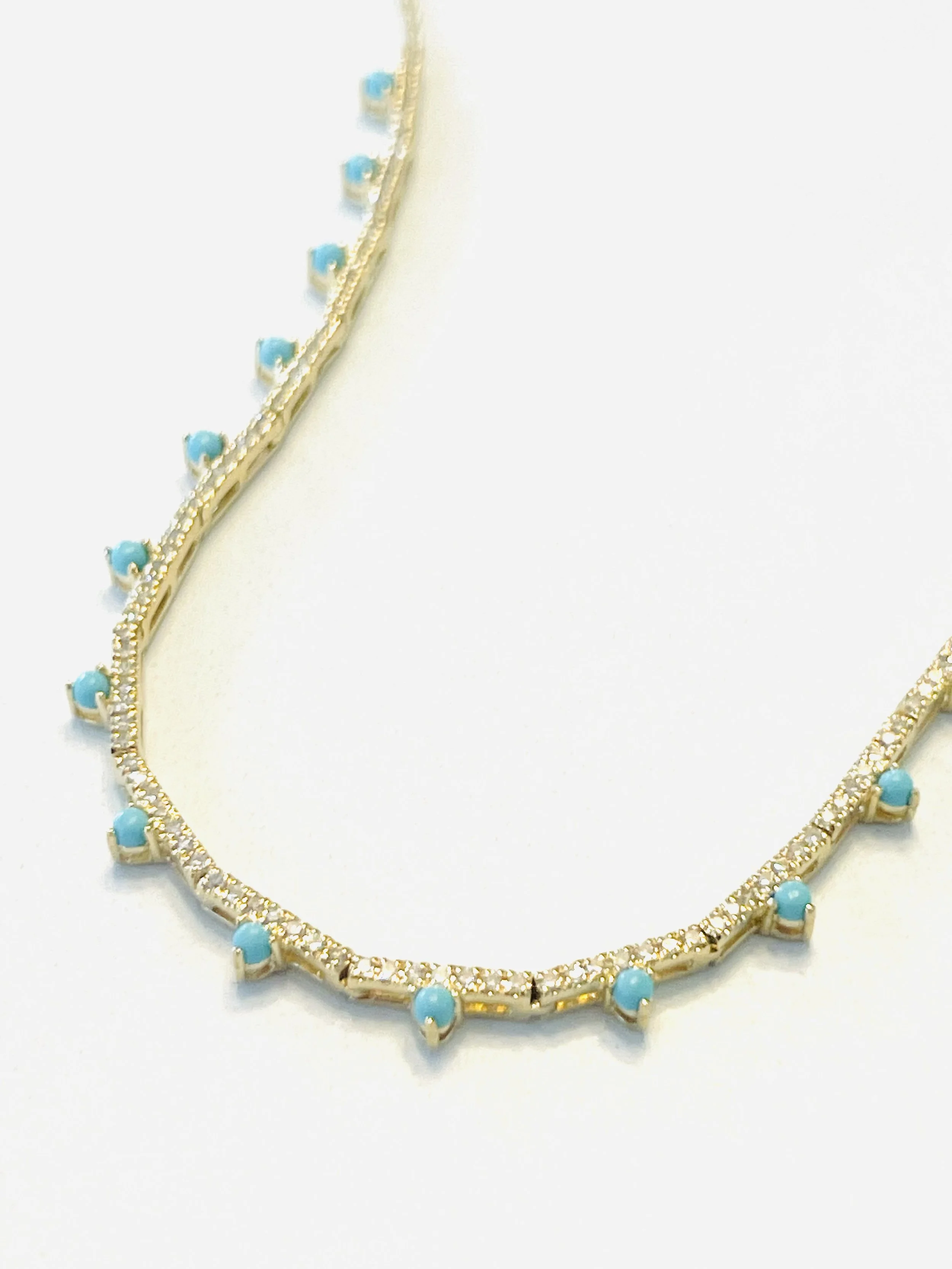 Gold necklace with small turquoise beads and clear gemstones, displayed against a white background.