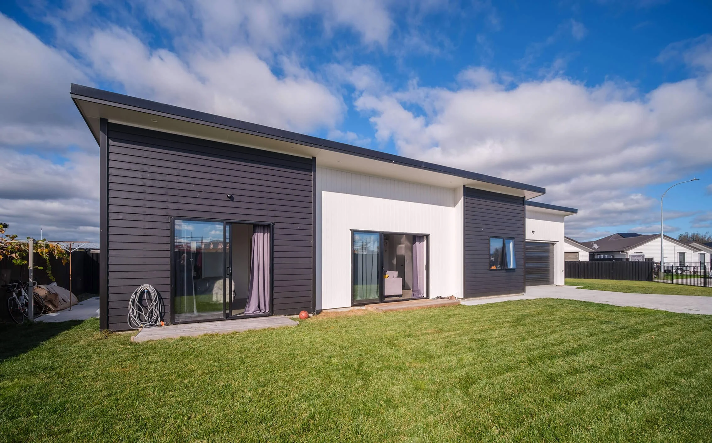 new house build mono pitch roof. weatherboard and duragroove cladding. sliding stacker doors and sectional garage door
