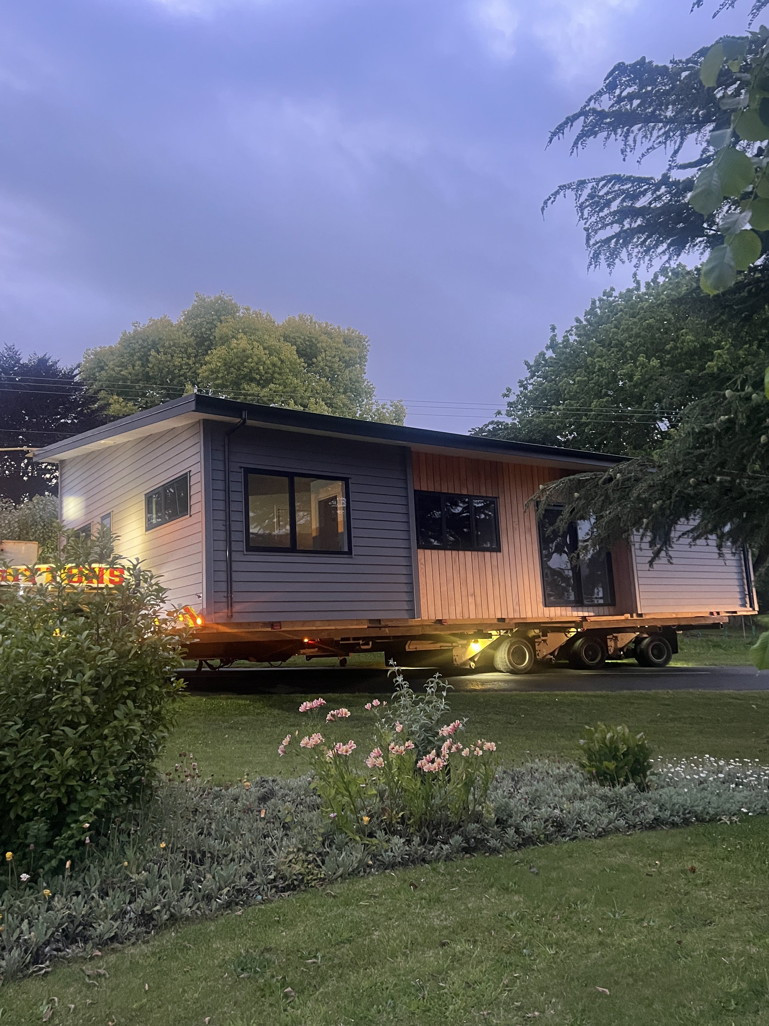 House being transported on a house moving trailer. lights on at dawn