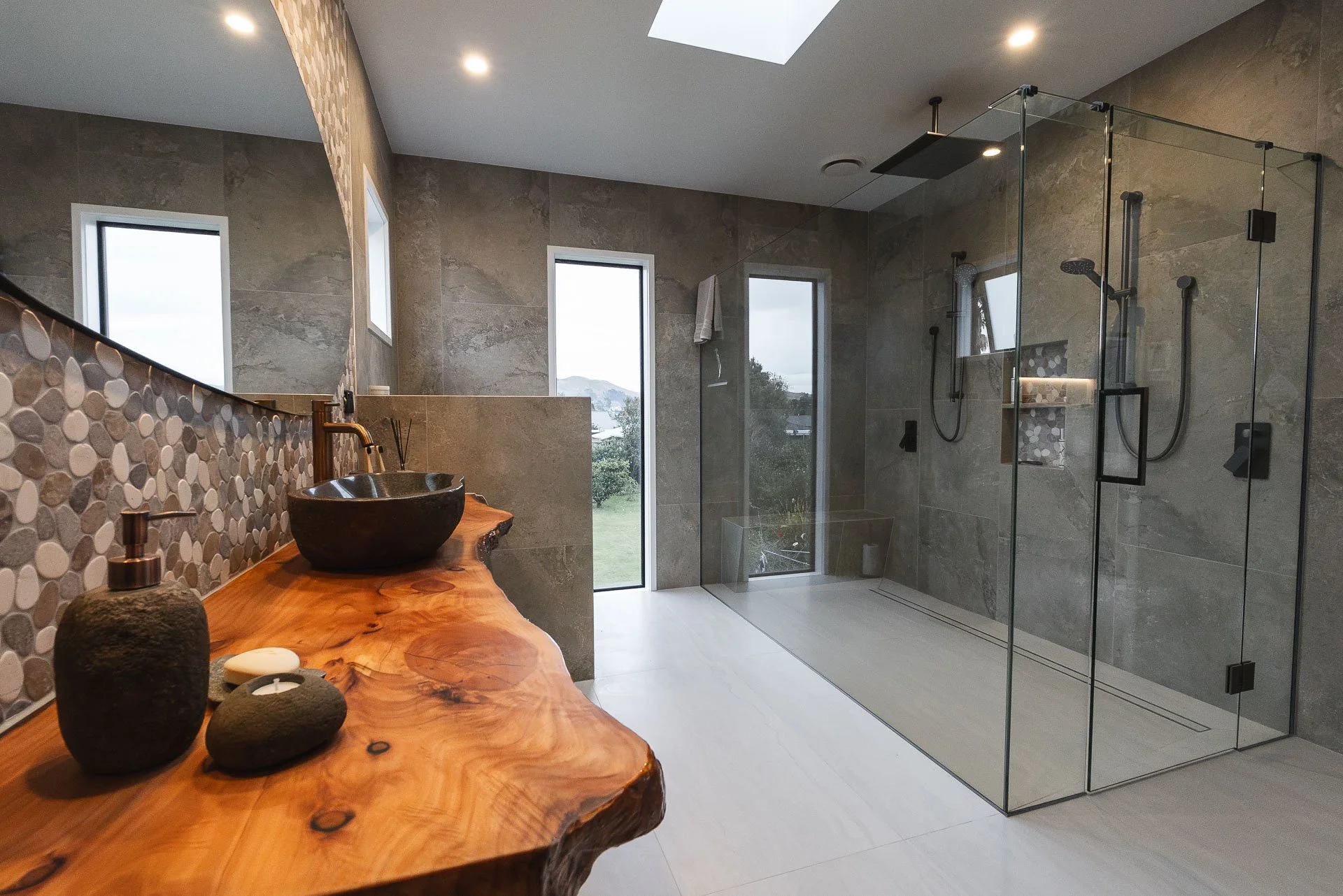 Custom live edge vanity top with stone basin and tiled shower.