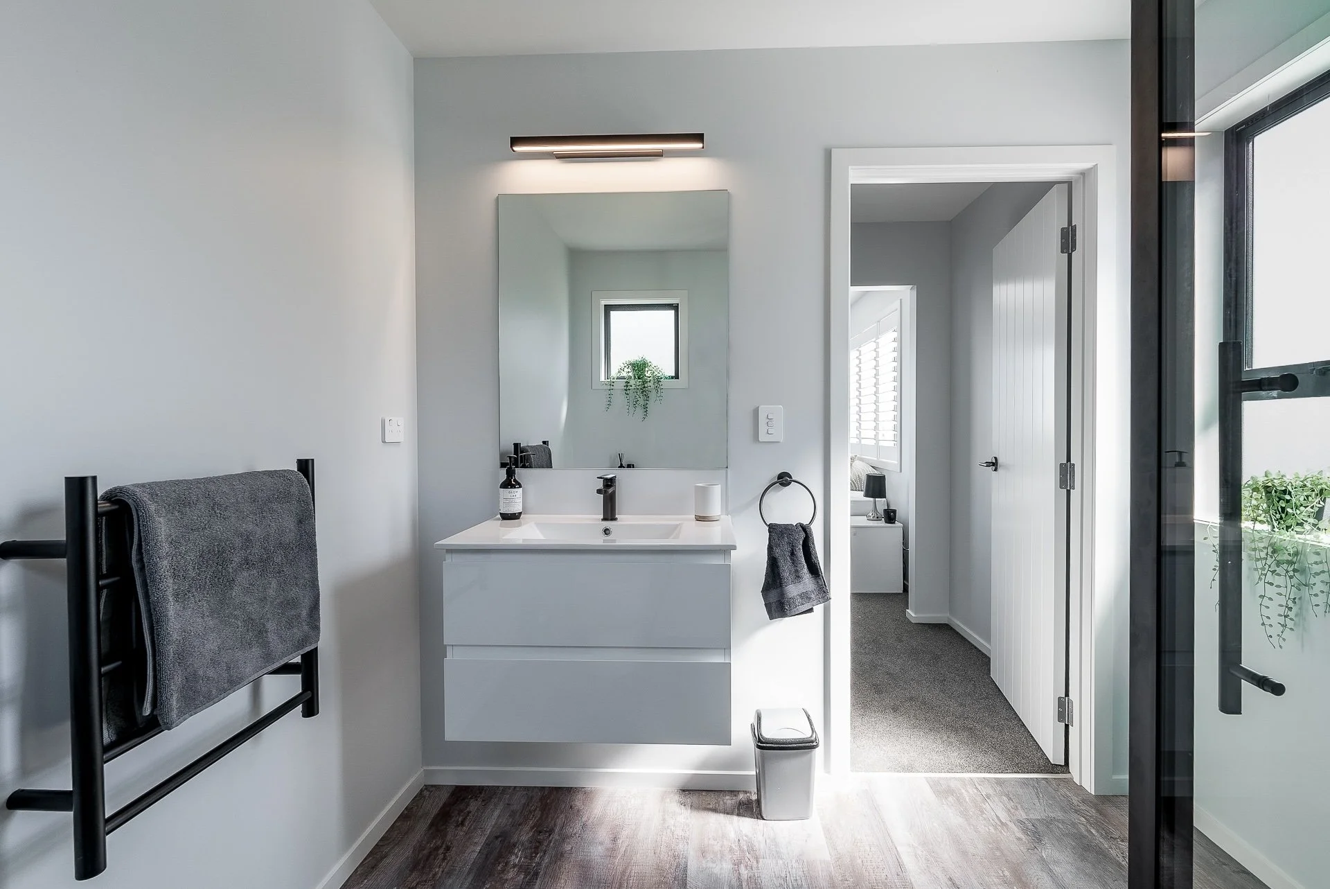 white wall hung vanity and heated towel rail, mirror and vanity light