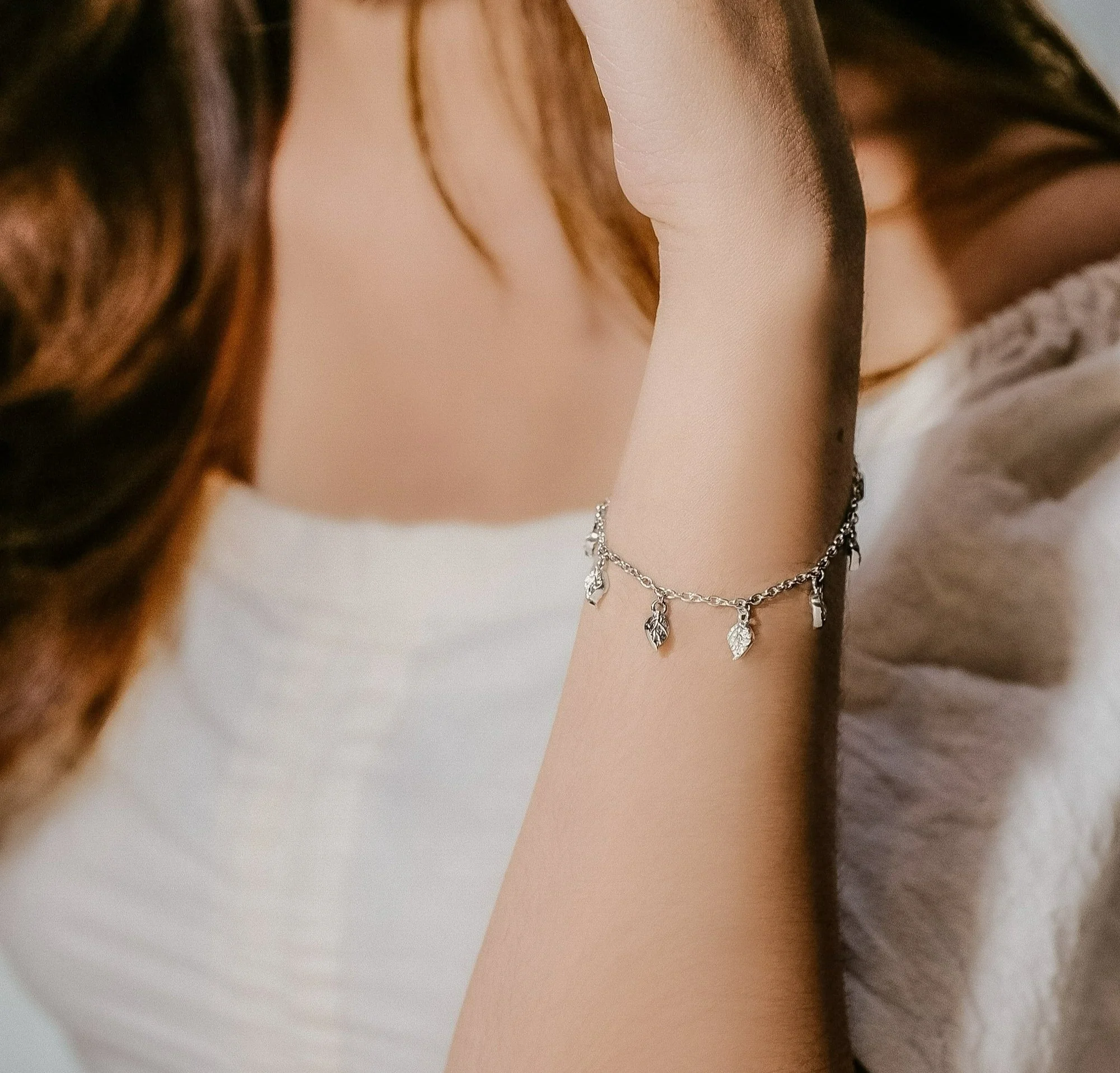 a models wrist wearing a left charm bracelet