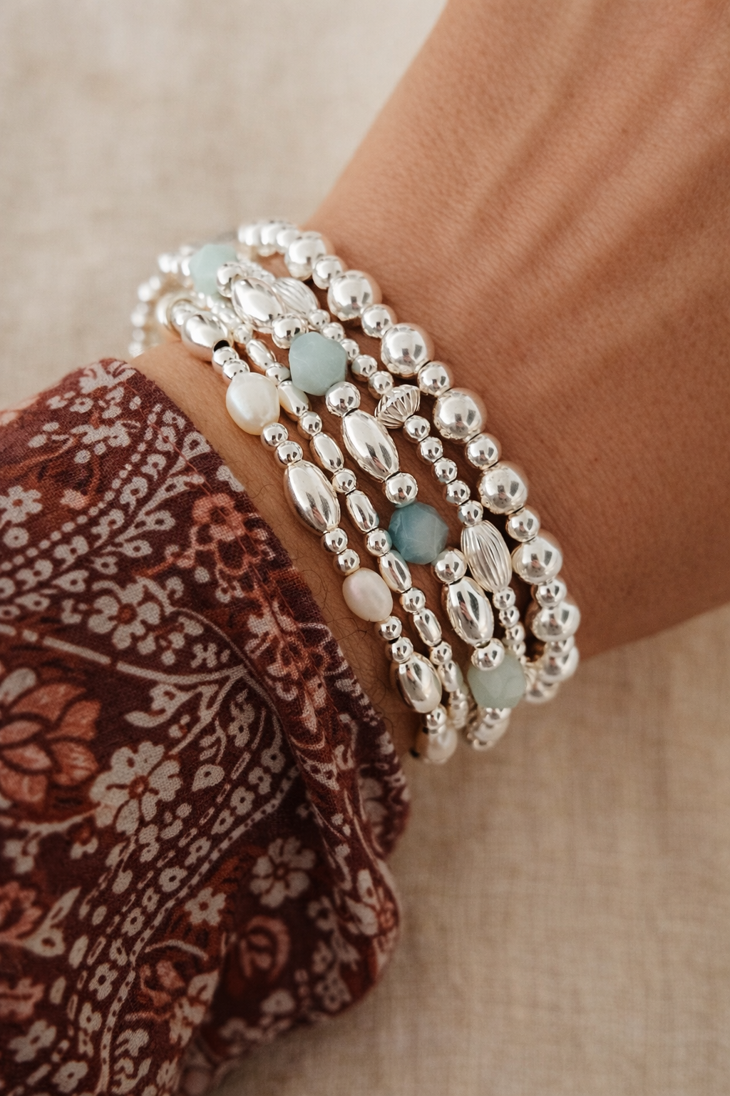 Silver bracelets on tanned wrist.png