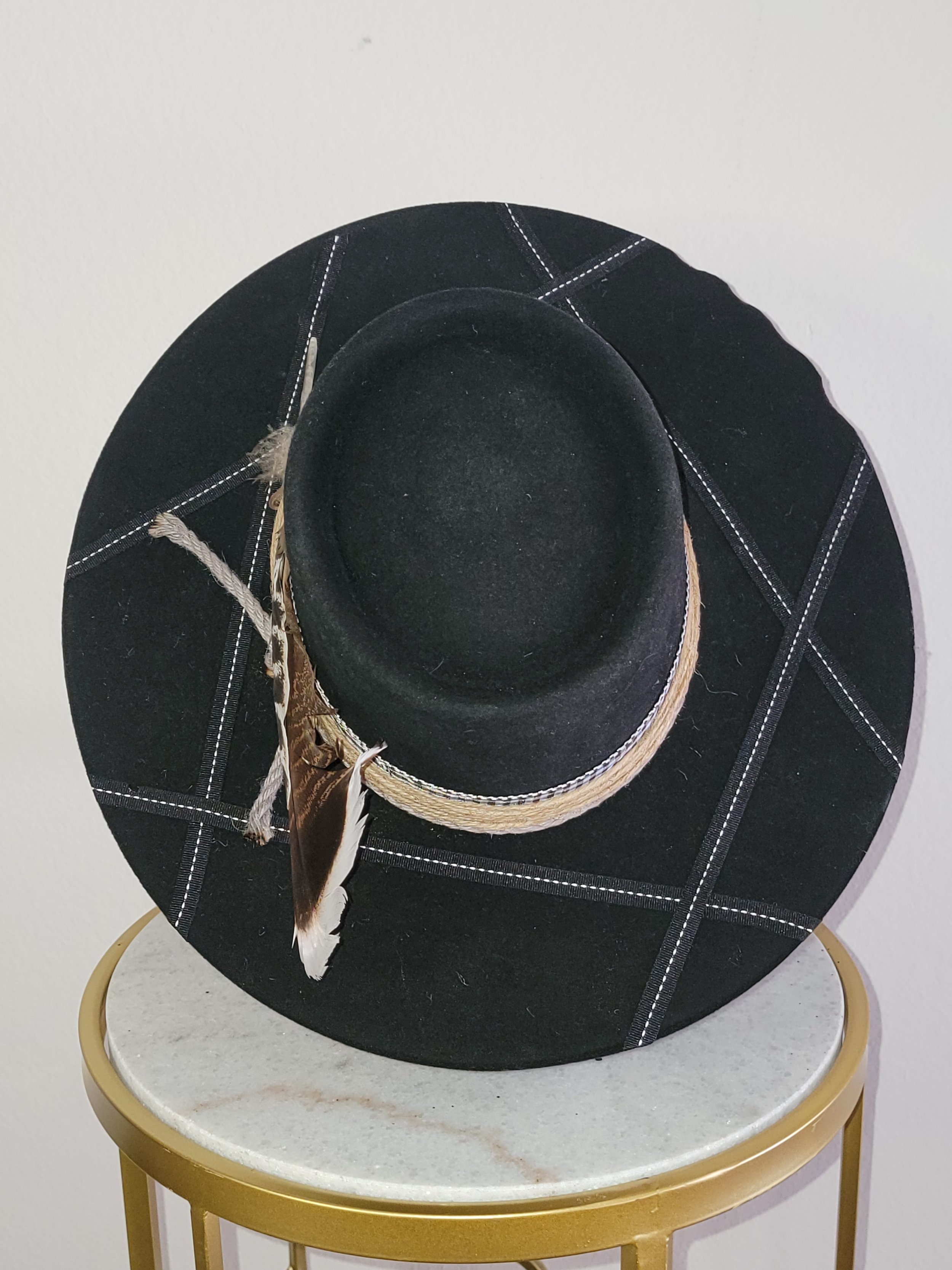 Black wide-brimmed Gambler hat with white stitching, lether and burlap bands, finished with black feathers.