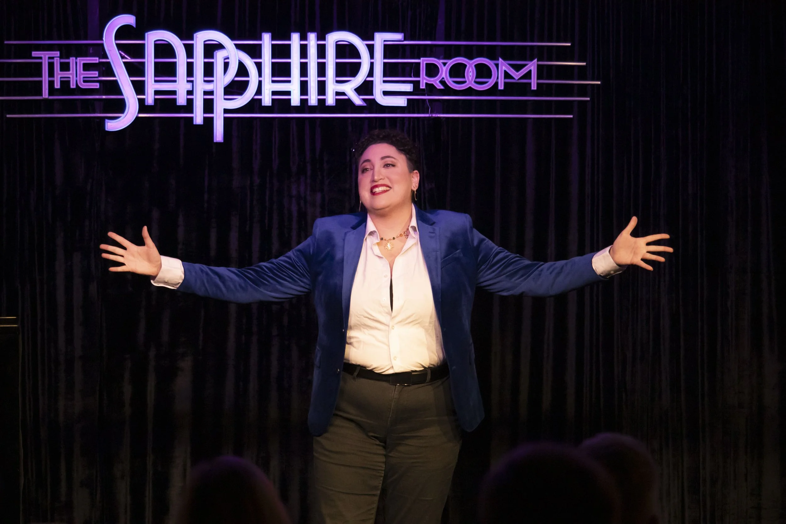 Performer with arms outstretched at The Sapphire Room stage