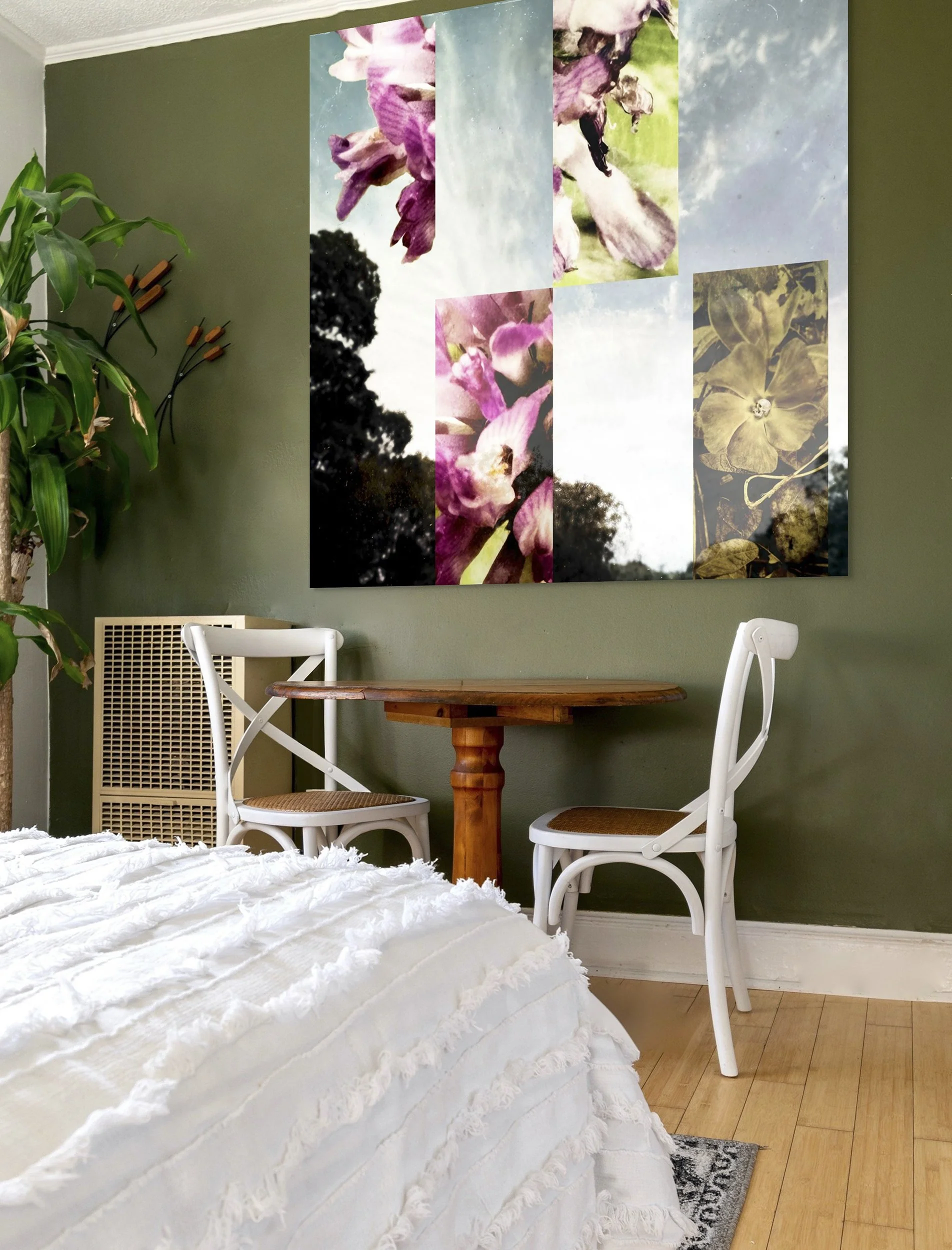 This mock-up shows print of Surrealistic digital composite, Clover, on green bedroom wall with round wood table, chairs, wooden flooring and large plant. e