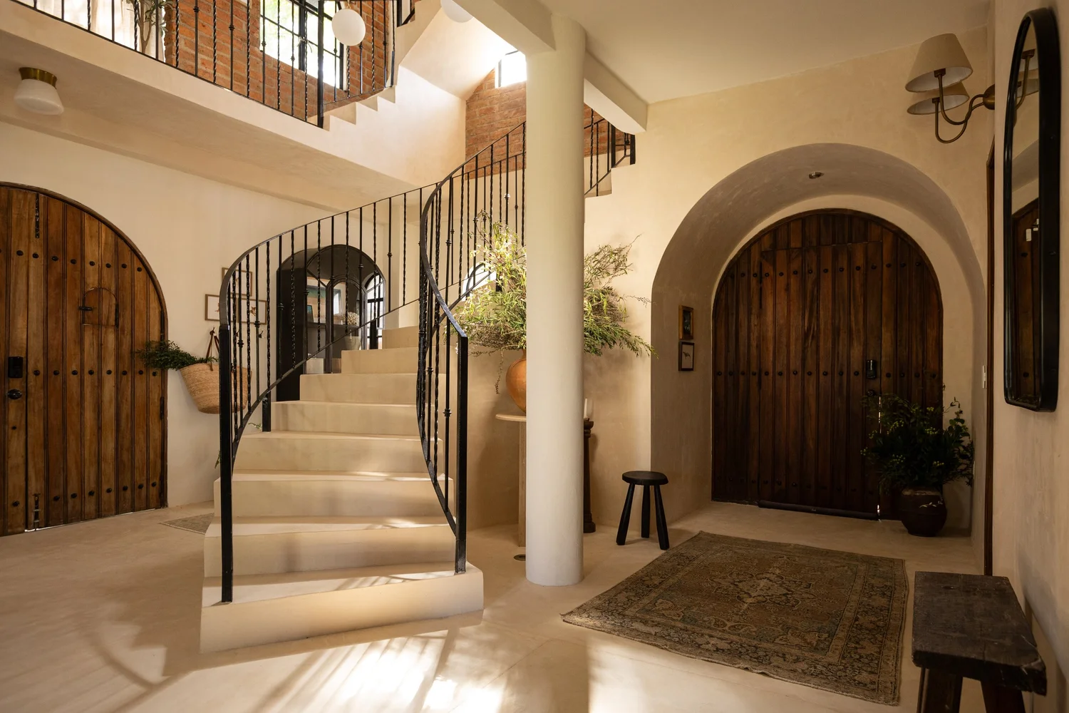 Entry hall with arched wood doors and a curved staircase at Casa Ensueño in Puerto Vallarta