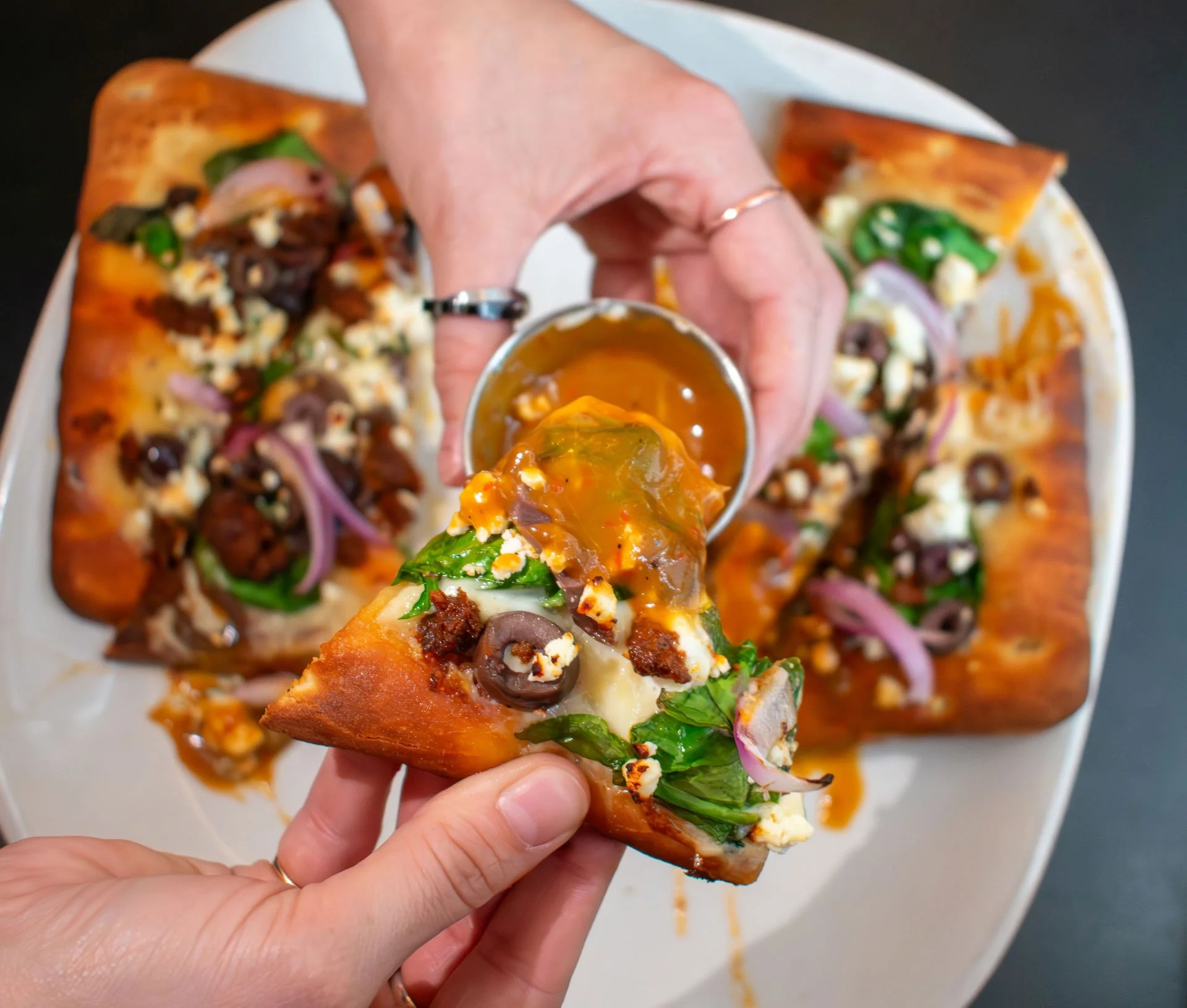 4-hand-with-rings-dipping-flatbread-pizza-into-orange-red-sauce-eat-drink-crave-2024.jpg
