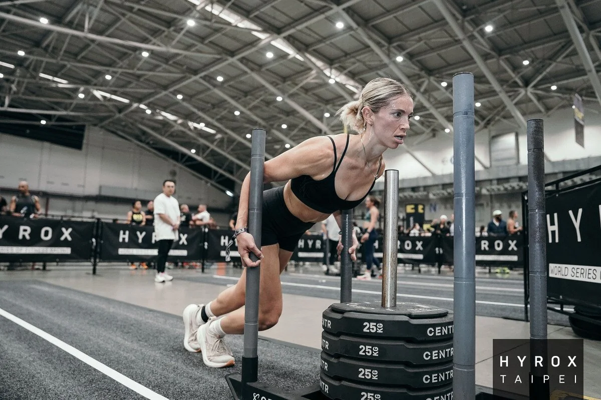 Woman pushing a sled competing at HYROX.