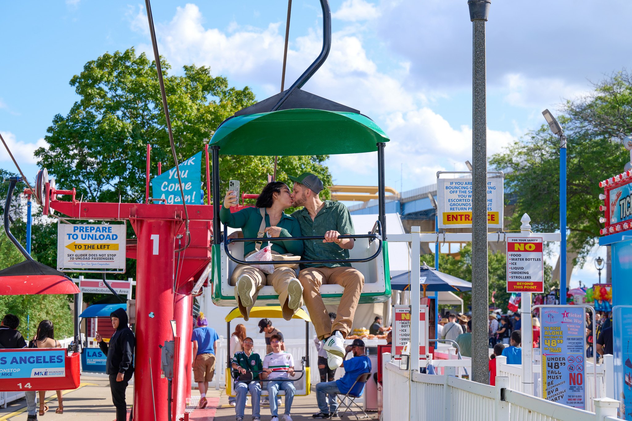 A couple sharing a kiss on a Ferris wheel at an amusement park during daytime.