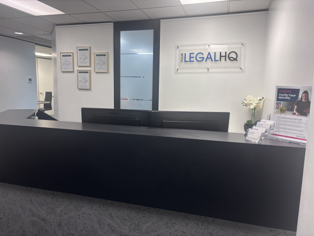 Reception desk with a sign reading "Your Legal HQ" on the wall }