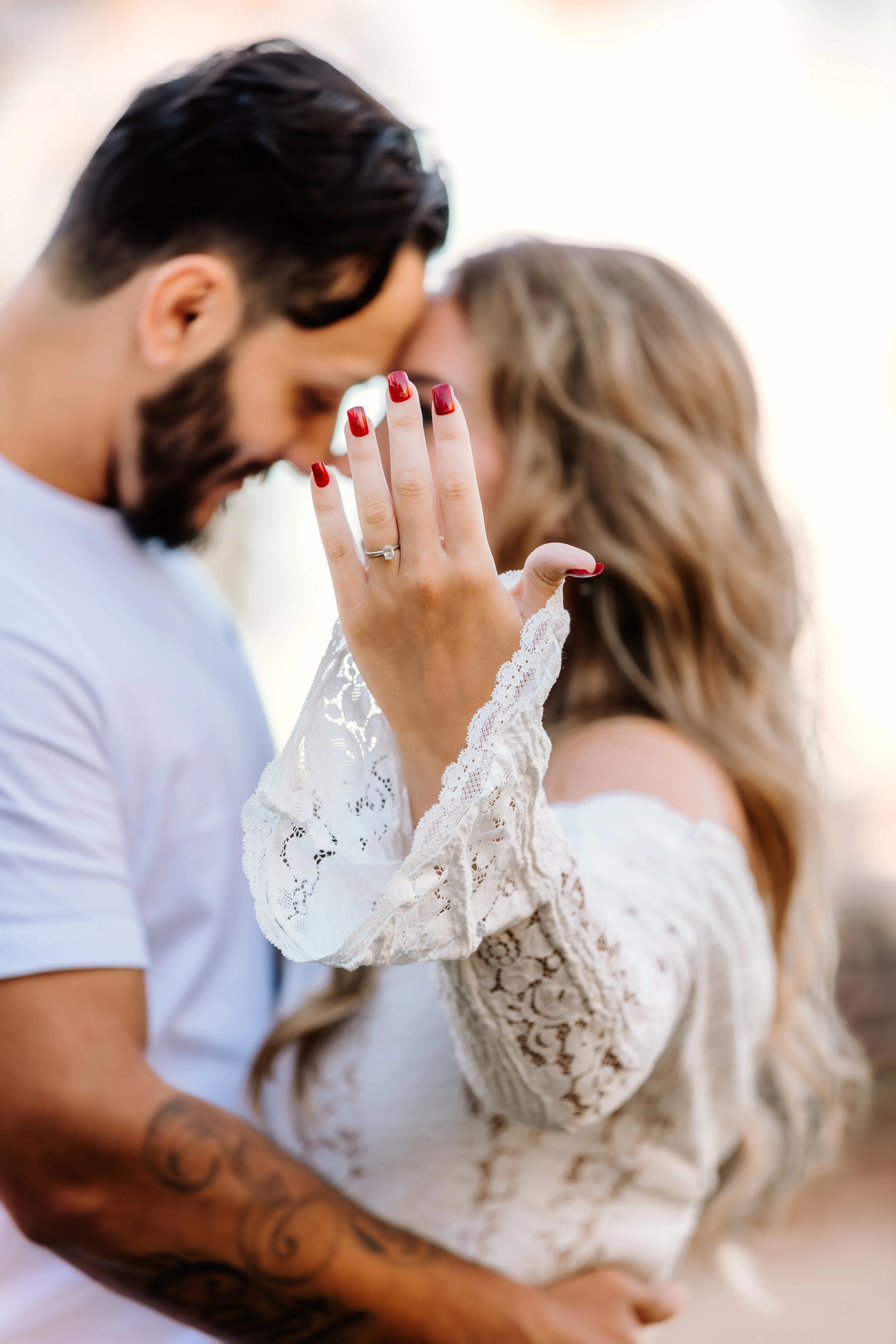 A couple sharing an intimate moment, with the woman's hand showing an engagement ring, and her face close to the man's, both with their eyes closed at Mary Jo Wegner Arboretum in Sioux Falls, South Dakota.