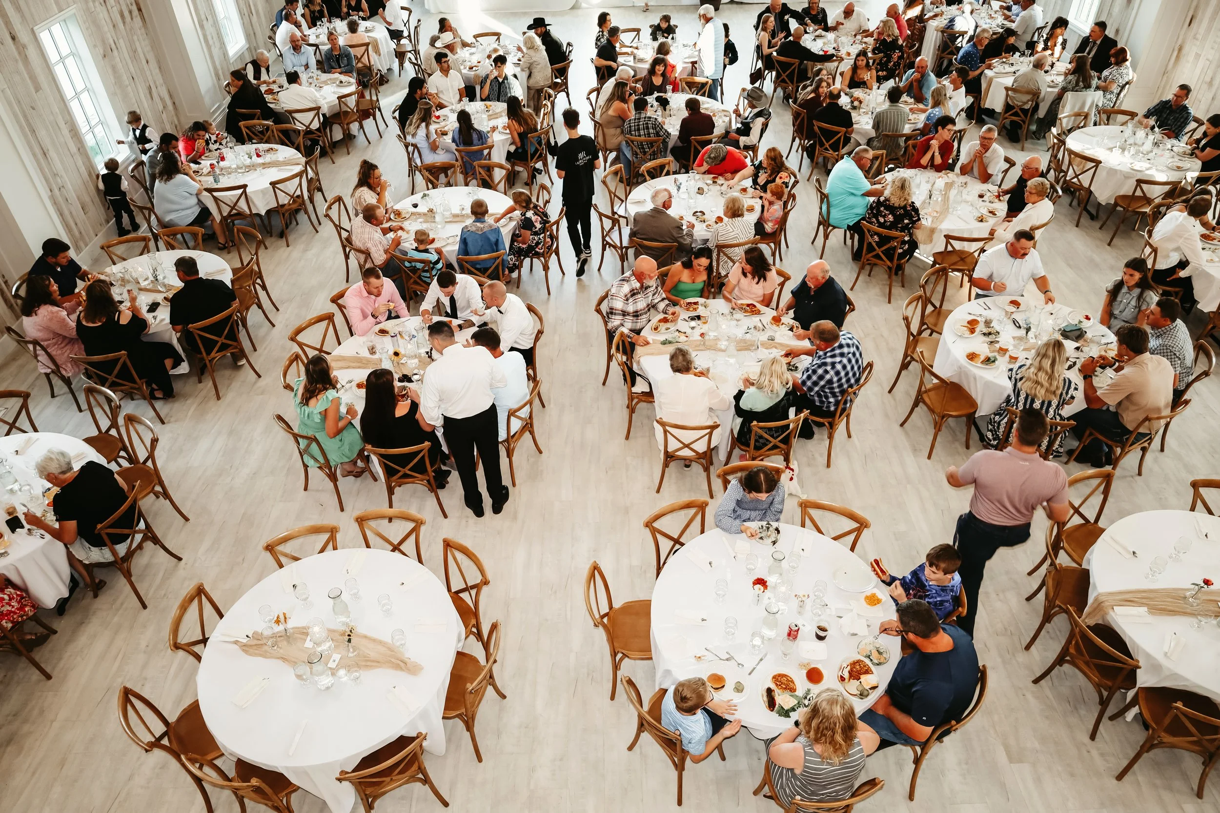 A large indoor banquet hall filled with round tables where people are eating and socializing during a celebration or event at Laurel Ridge in Sioux Falls SD.