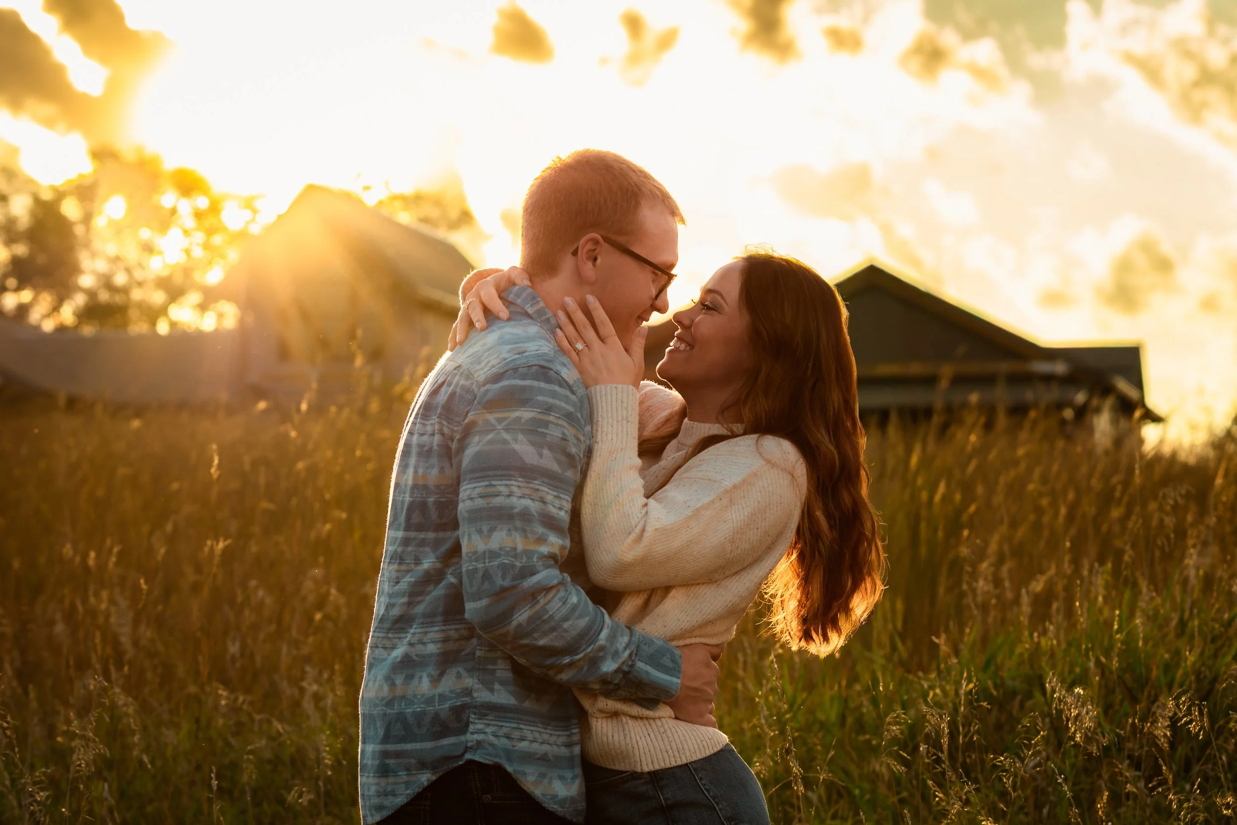 A couple embracing each other in a field at sunset with a building in the background at Good Earth State Park in Sioux Falls, South Dakota.