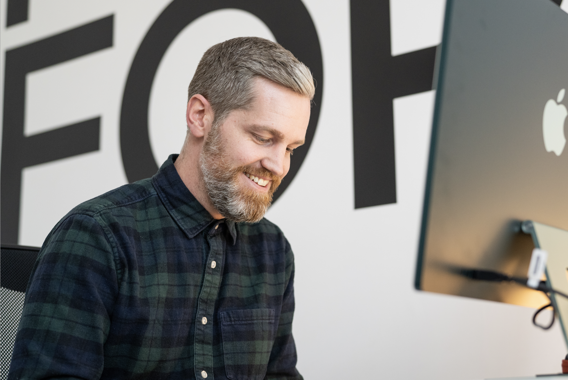 Male film videographer smiling at Mac
