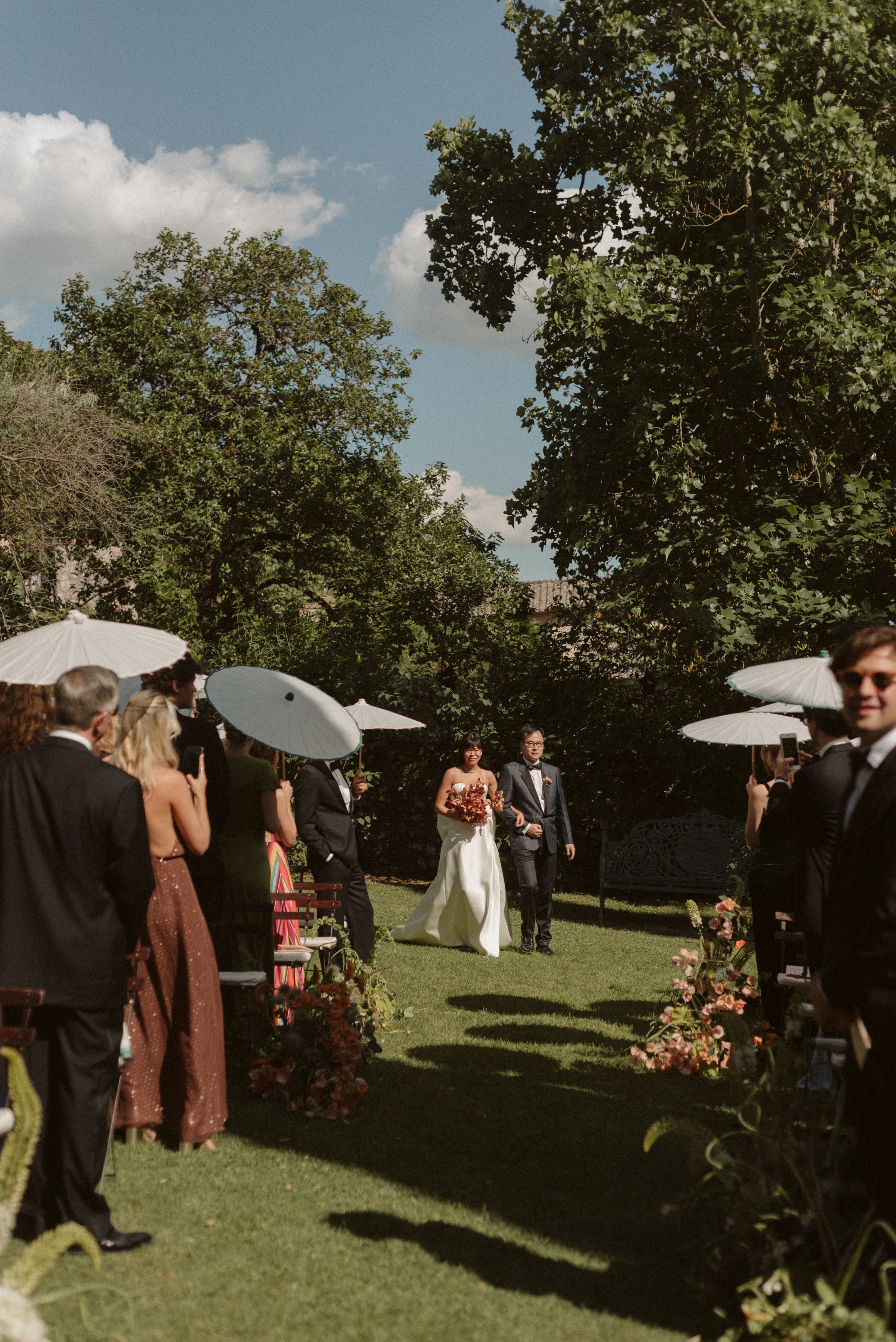  Bride and groom walking down the aisle at Villa Cetinale. Bride holding a wedding bouquet with orchids.  