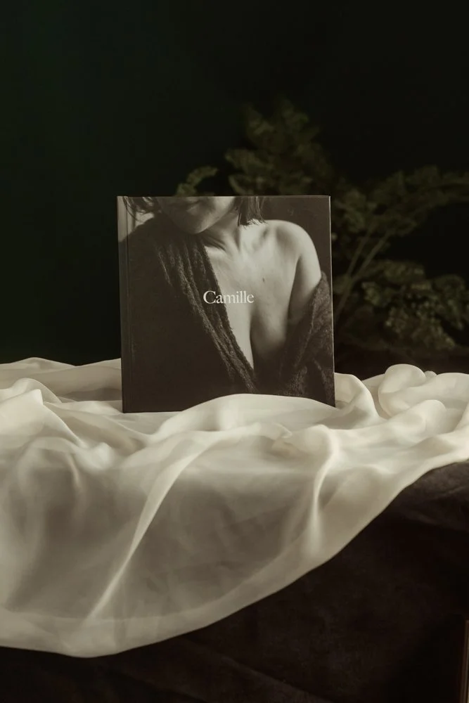 Photo d'un livre posé sur un morceau de soie. La couverture est une photo noir et blanc d'un buste de femme et il est inscrit "Camille".