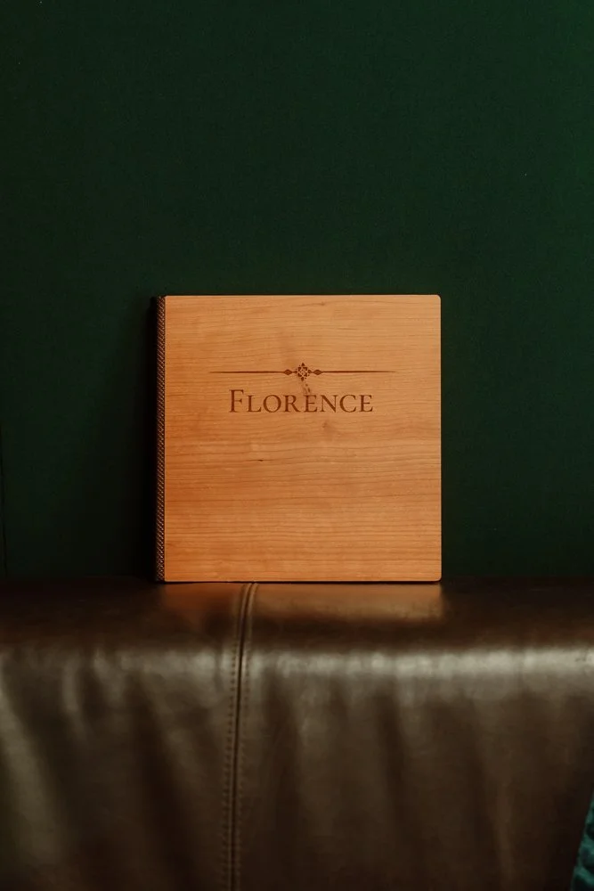 Photo d'un album photo à la couverture en bois de cerisier. Le titre, gravé dans le bois, est un prénom de femme : Florence.