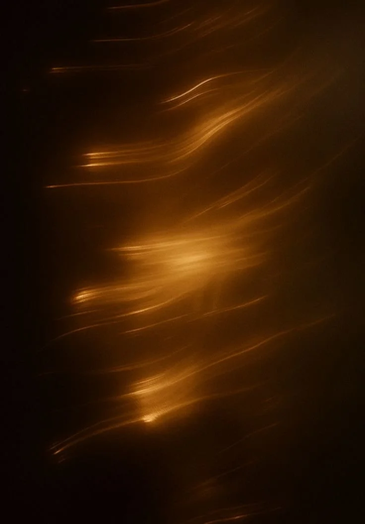 Abstract image with streaks of warm light on a dark background.