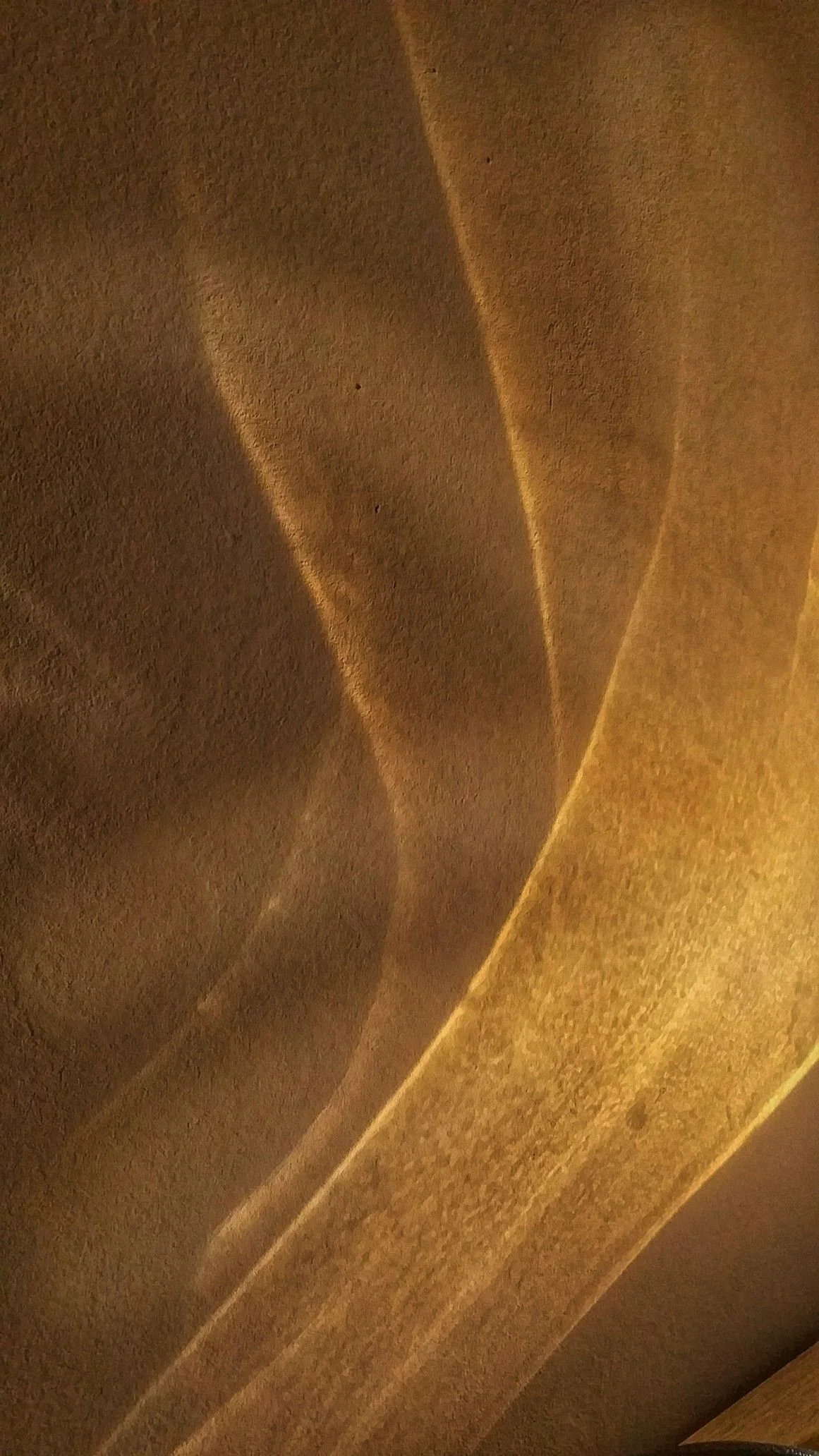 Close-up of a surface with warm, golden light creating soft shadows and subtle textures.