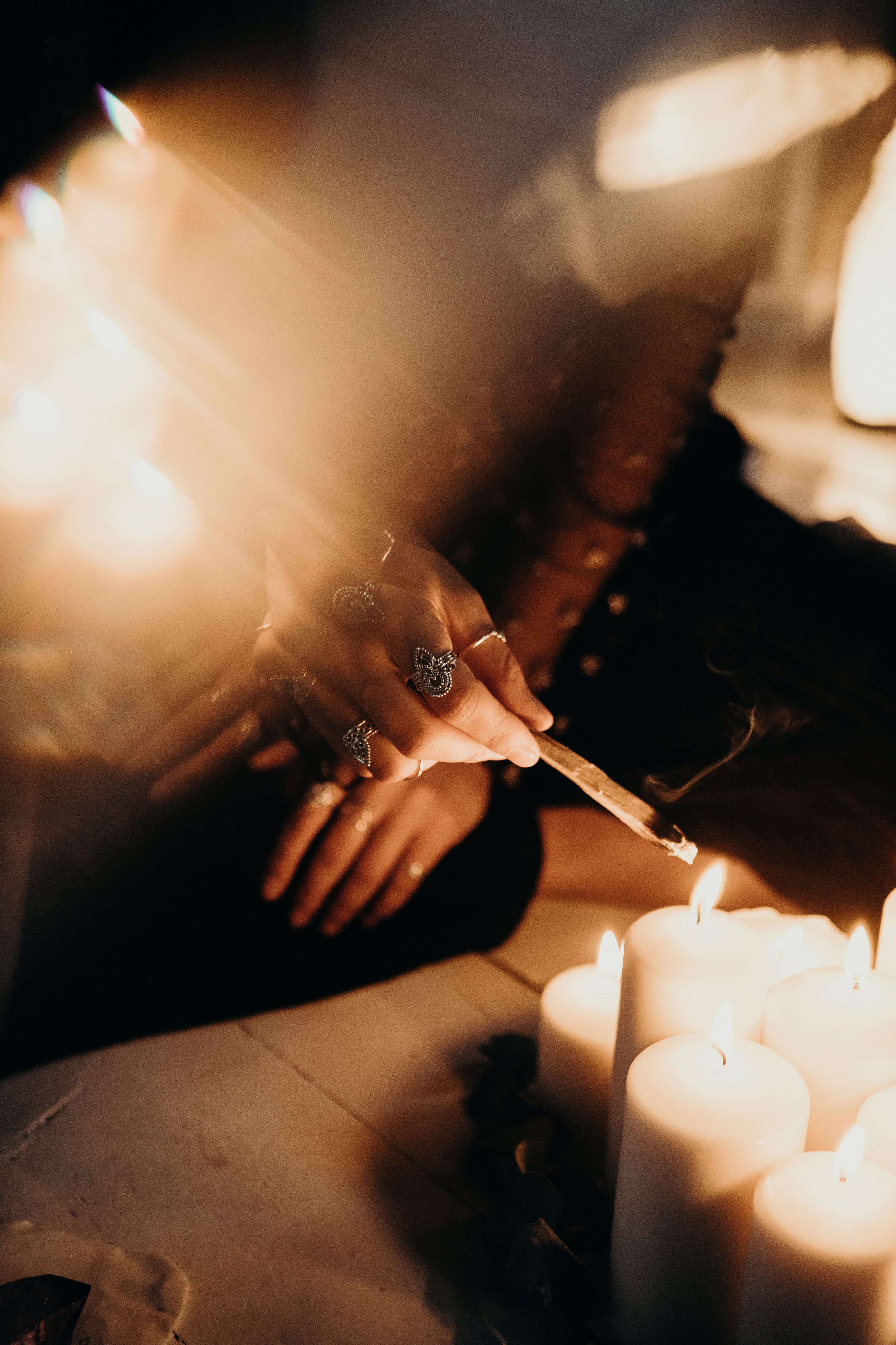 Person lighting candles with a matchstick, surrounded by lit candles in a dimly lit setting.