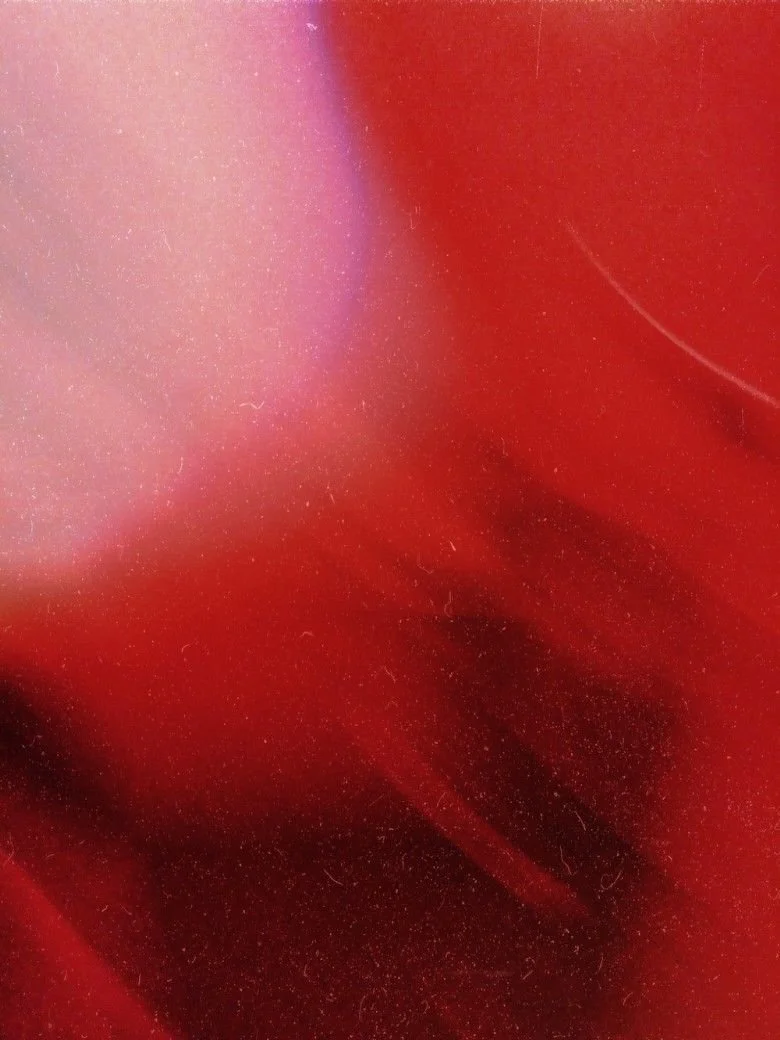 Close-up of a shiny, red, reflective surface with some streaks and small particles.
