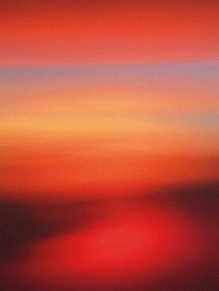Blurred image of a colorful sunset sky with shades of orange, pink, purple, and red.