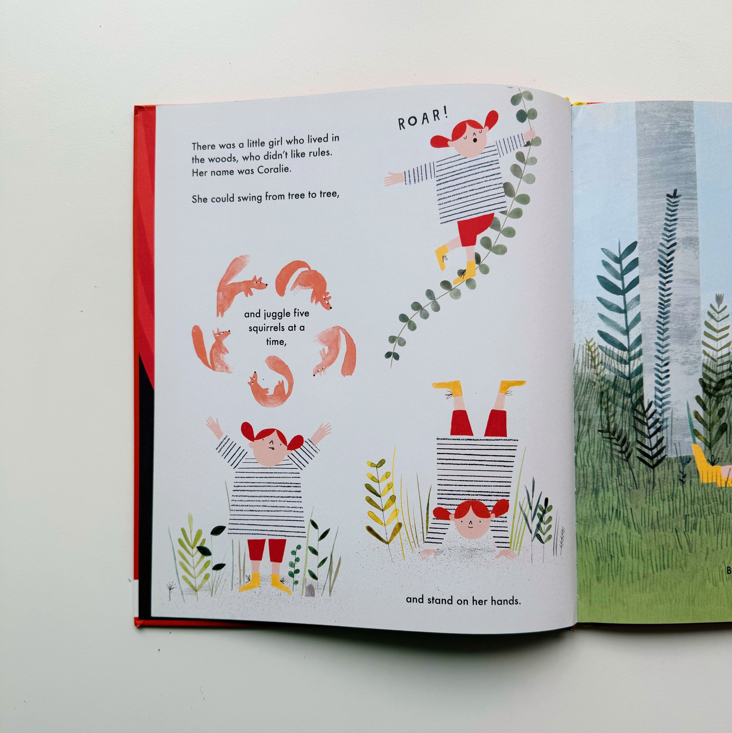 An open children's book with colorful illustrations of a girl with red hair, wearing striped shirt and red shorts, standing on her hands and holding a leafy branch. There are also small animals like squirrels or foxes around her. The page includes te