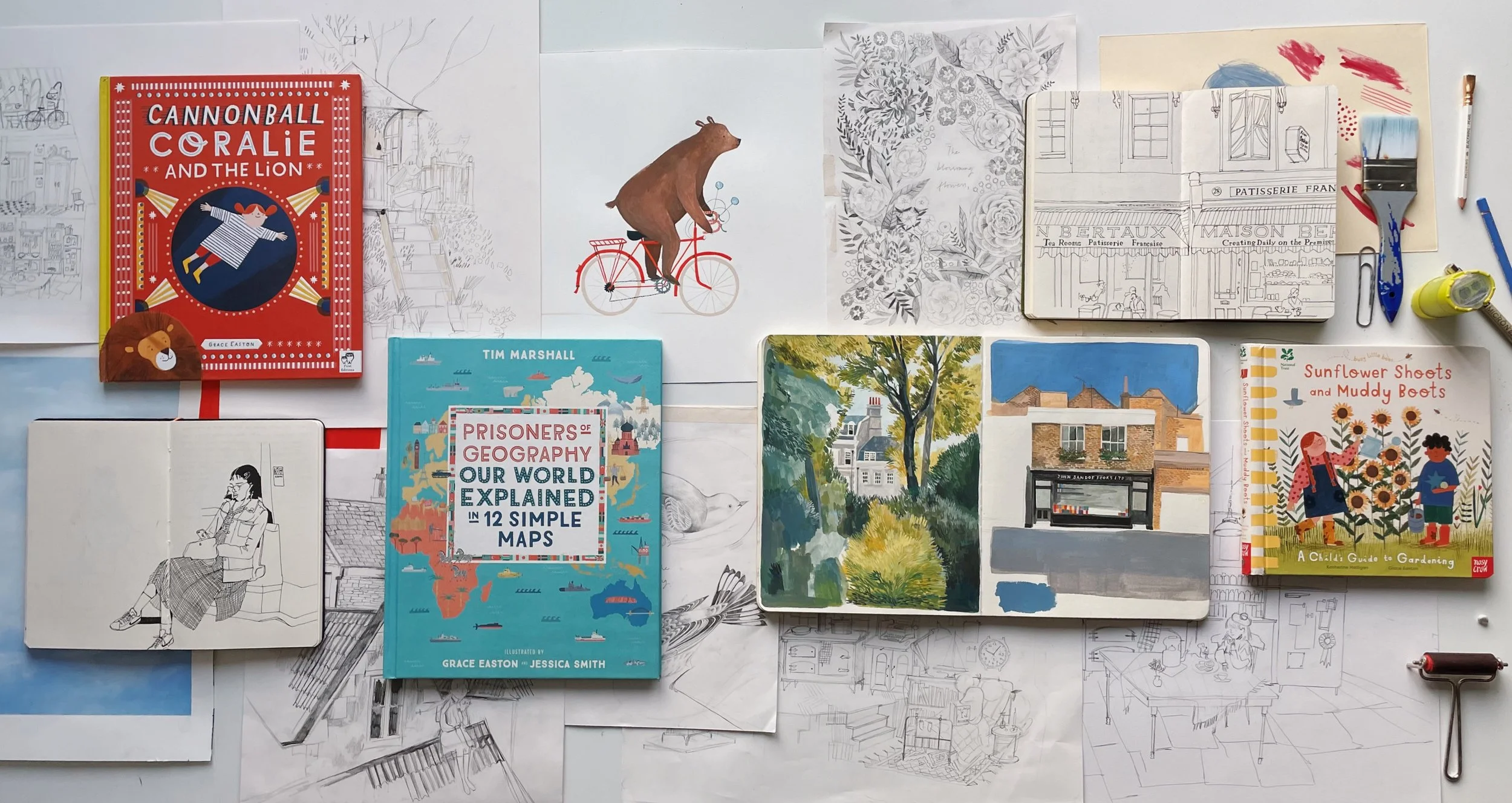 A collection of books, sketches, and illustrations on a workspace table, including children's books, architectural sketches, and nature-themed art, with drawing tools such as pencils and a paintbrush.