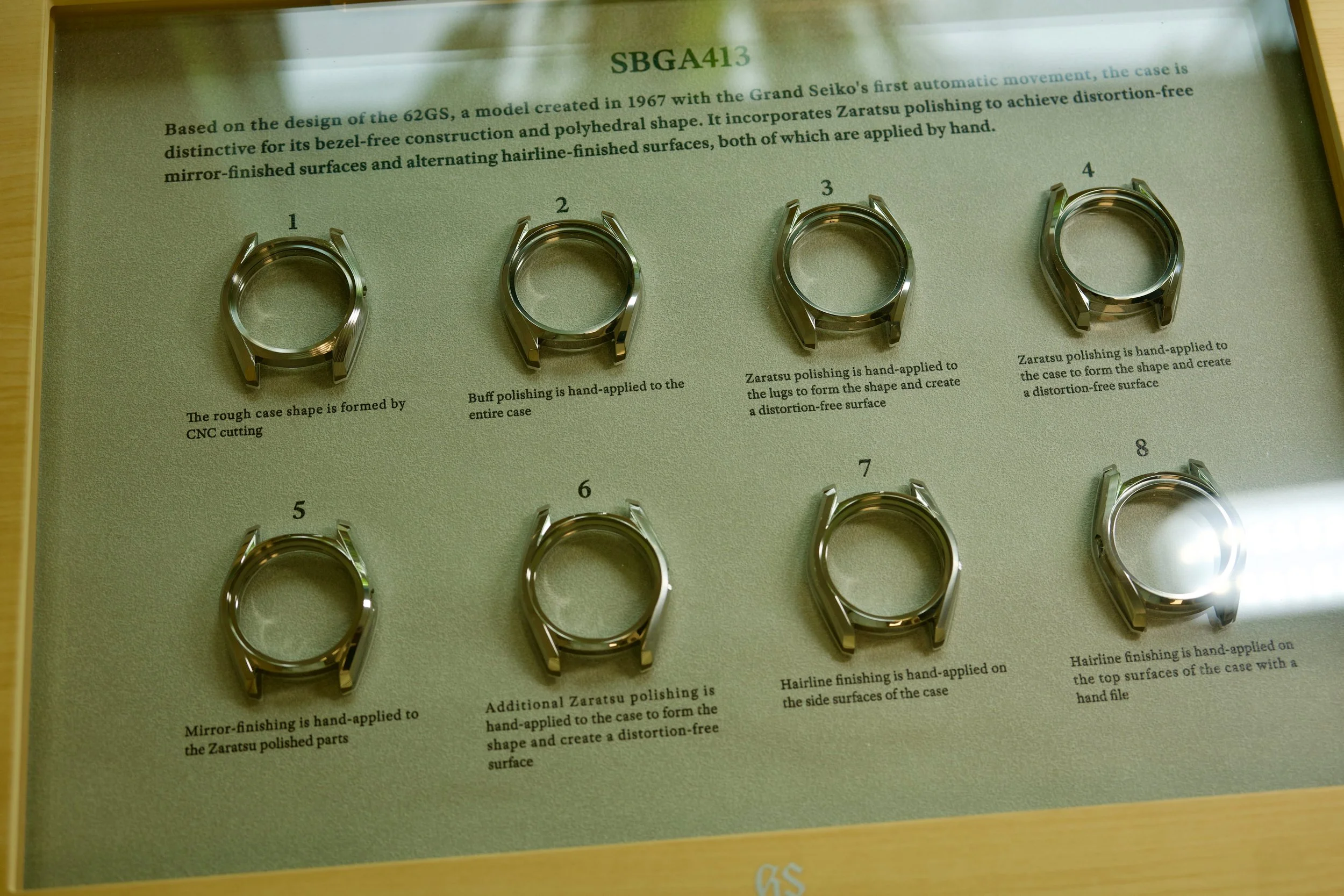 Display showing the Grand Seiko SBGA413 case finishing process, including Zaratsu polishing and hand-applied hairline finishing.
