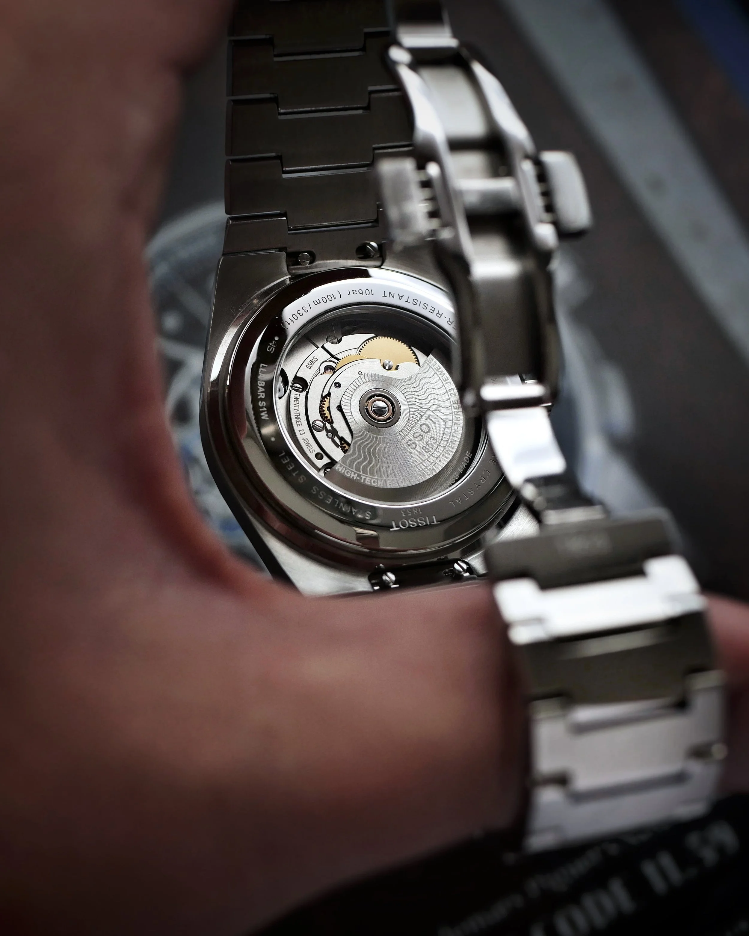 Tissot PRX Powermatic 80 automatic movement visible through the exhibition caseback, with the bracelet clasp open
