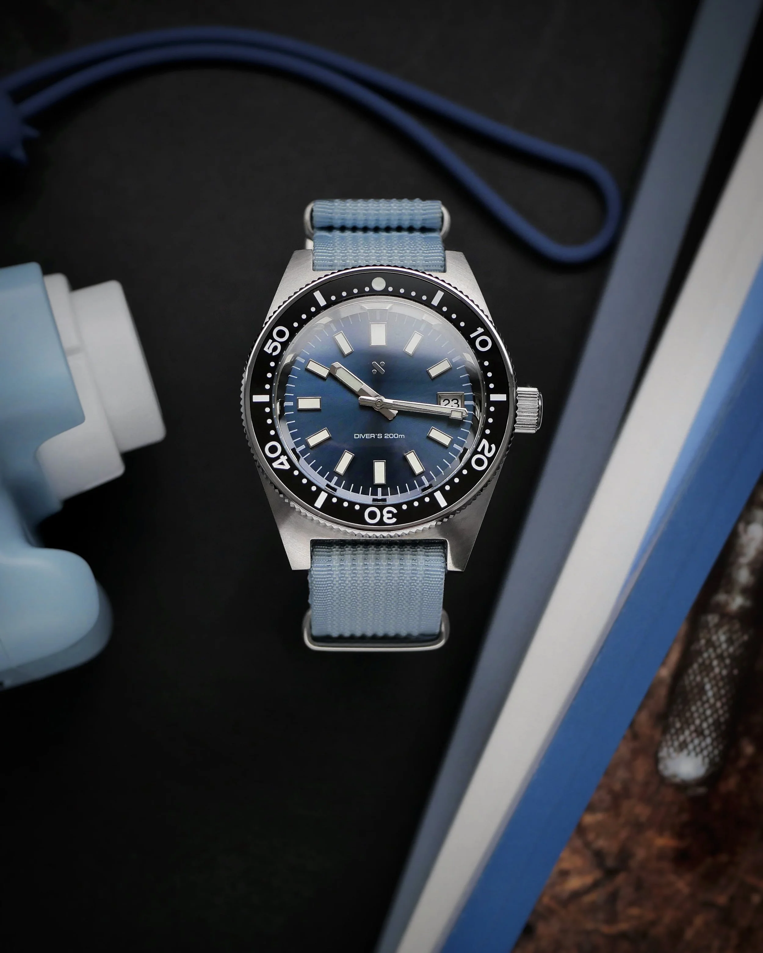 Namoki NMK07 62MAS homage with a blue dial and pale blue woven strap on a dark surface.