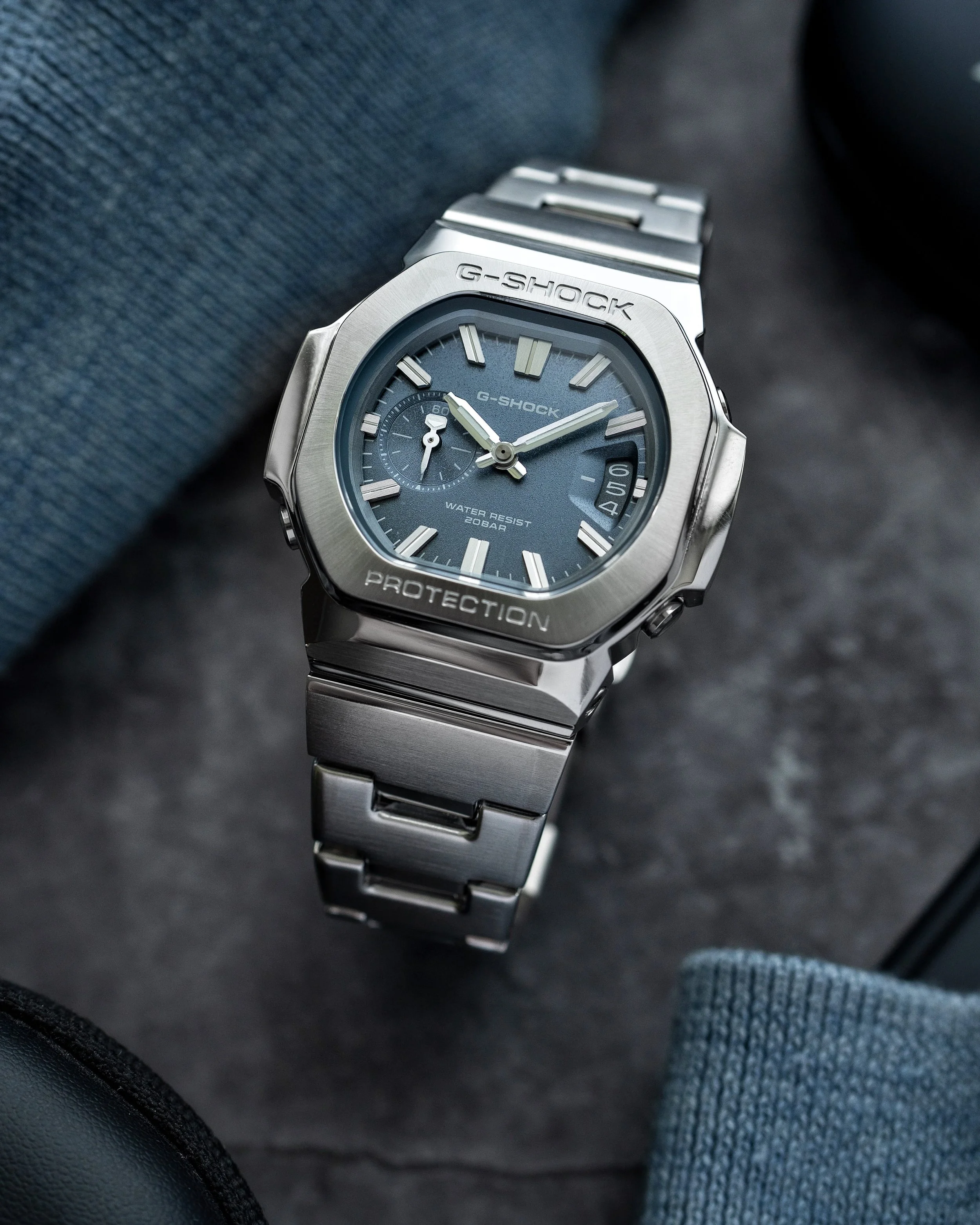 Casio G-SHOCK GMC-2500D-1A2 CasioNaut with a textured blue analogue dial, raised silver hour markers, brushed stainless steel bezel and matching metal bracelet.