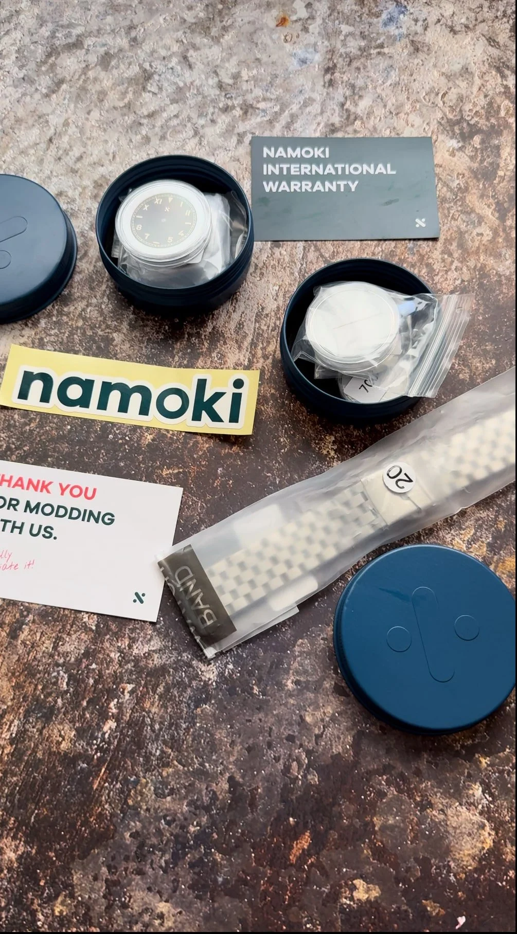 Namoki watch-build components in packaging, with a five-link bracelet and warranty card