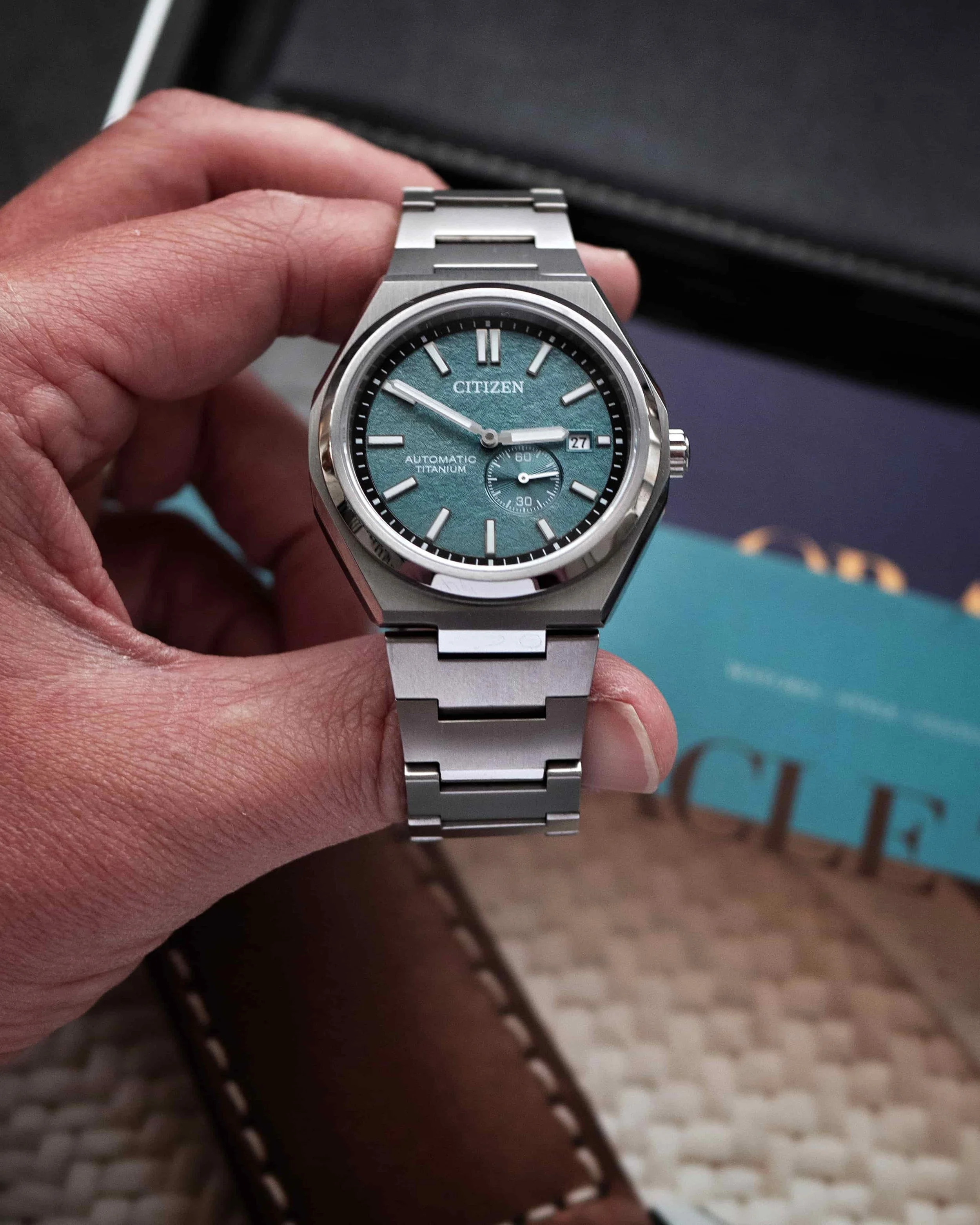 Citizen Zenshin NJ0180-80X Super Titanium shown handheld, highlighting the green textured dial and titanium bracelet.