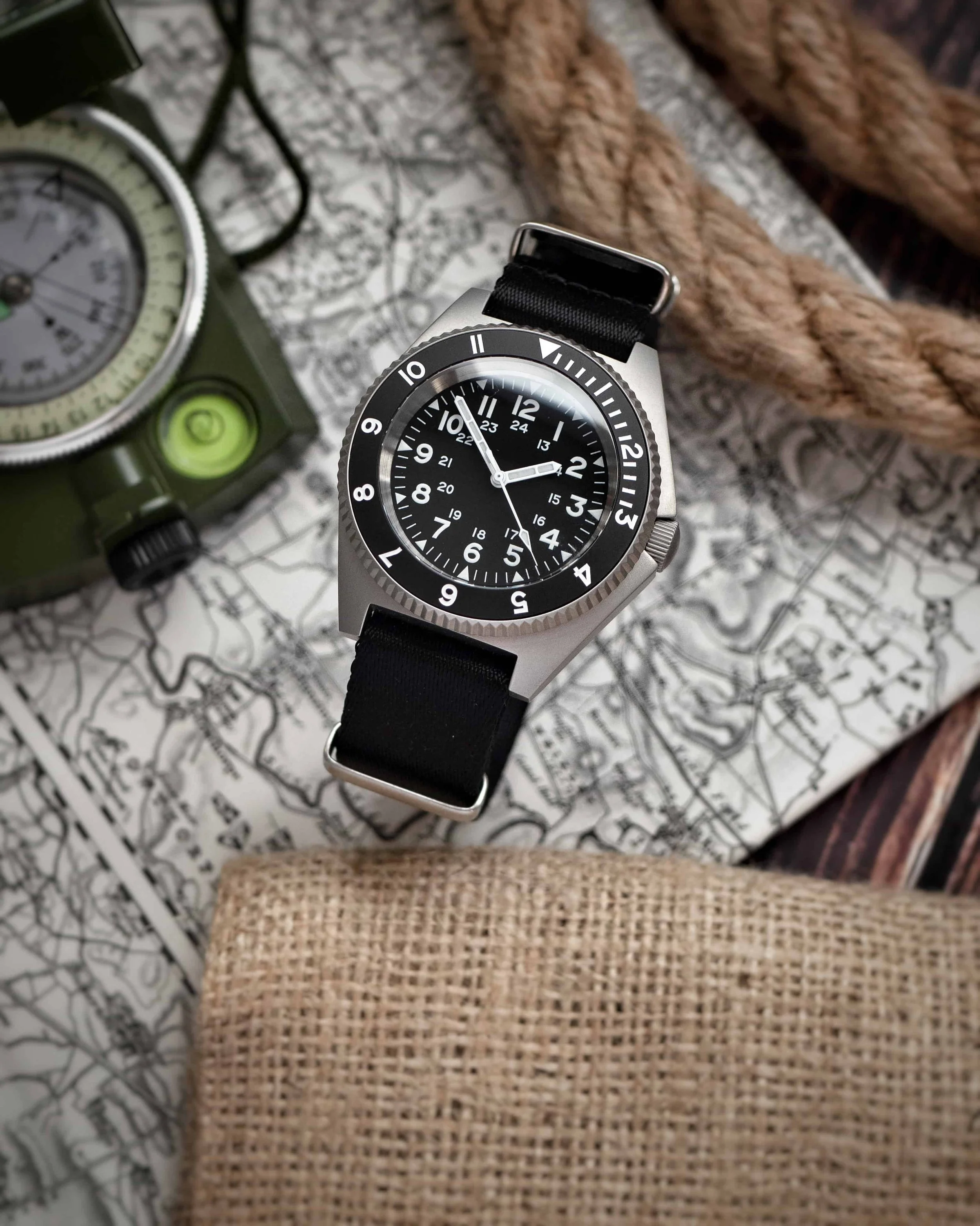 Namoki NMK20 with a black NATO strap on a map beside a compass and rope