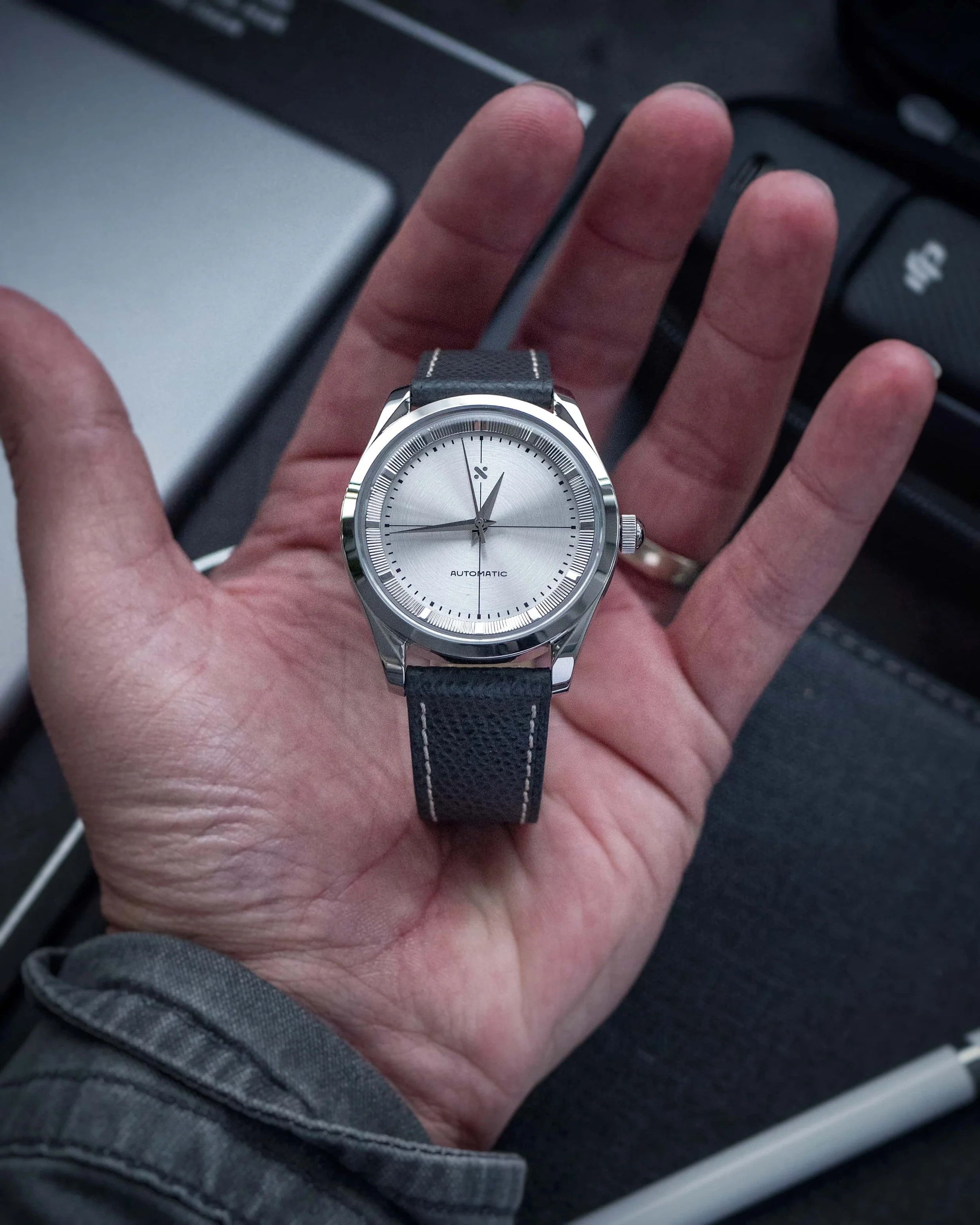 Completed silver-dial Namoki watch resting in the palm