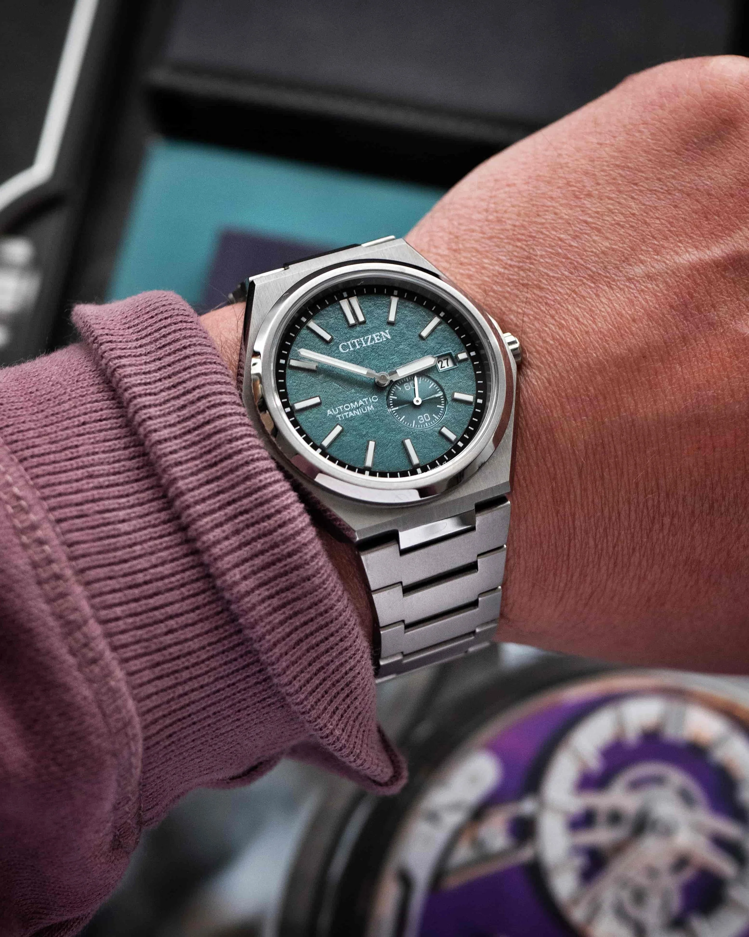 Citizen Zenshin NJ0180-80X Super Titanium on wrist with green textured dial and titanium bracelet.