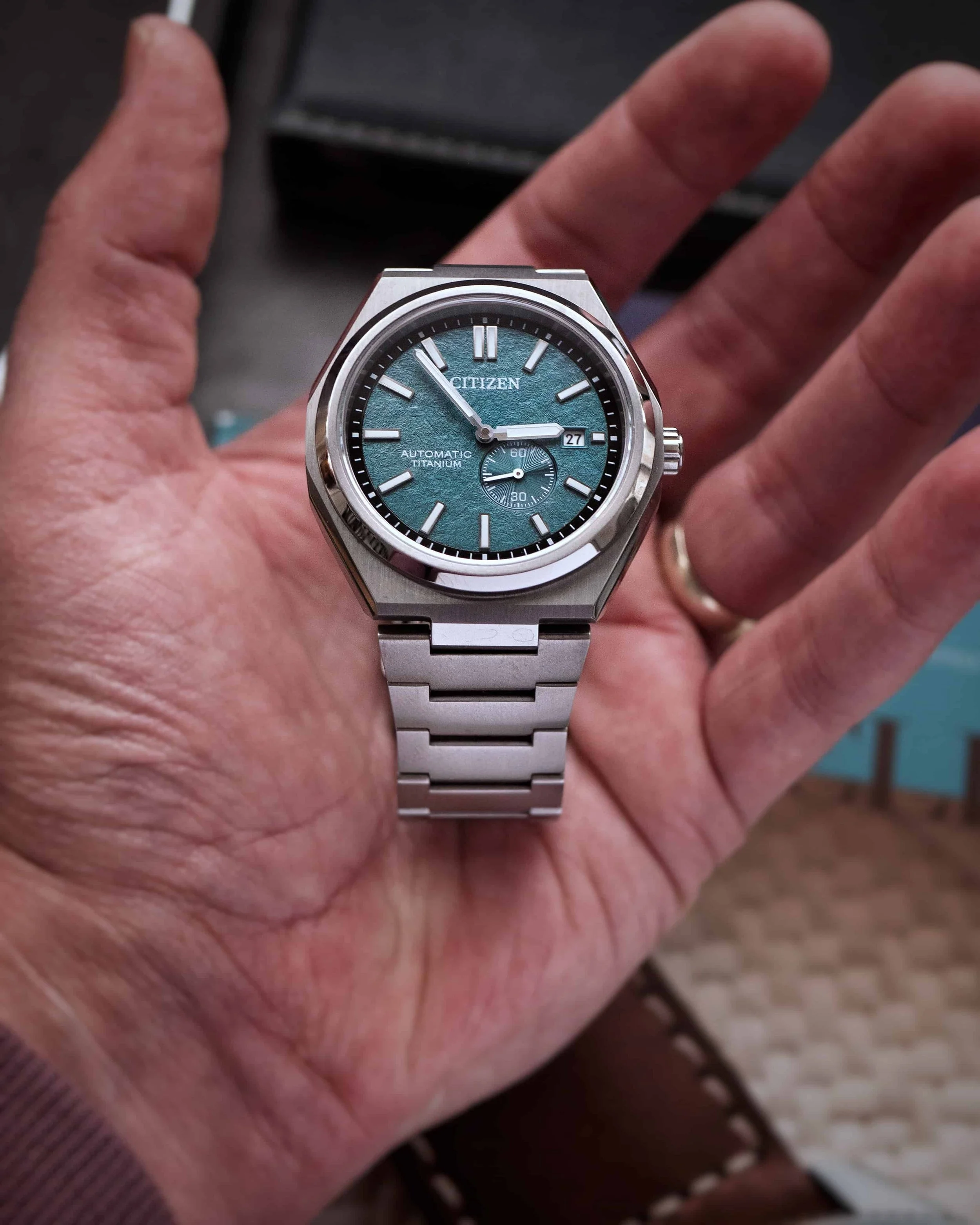 Citizen Zenshin NJ0180-80X Super Titanium shown in hand, highlighting the green textured dial and titanium bracelet.