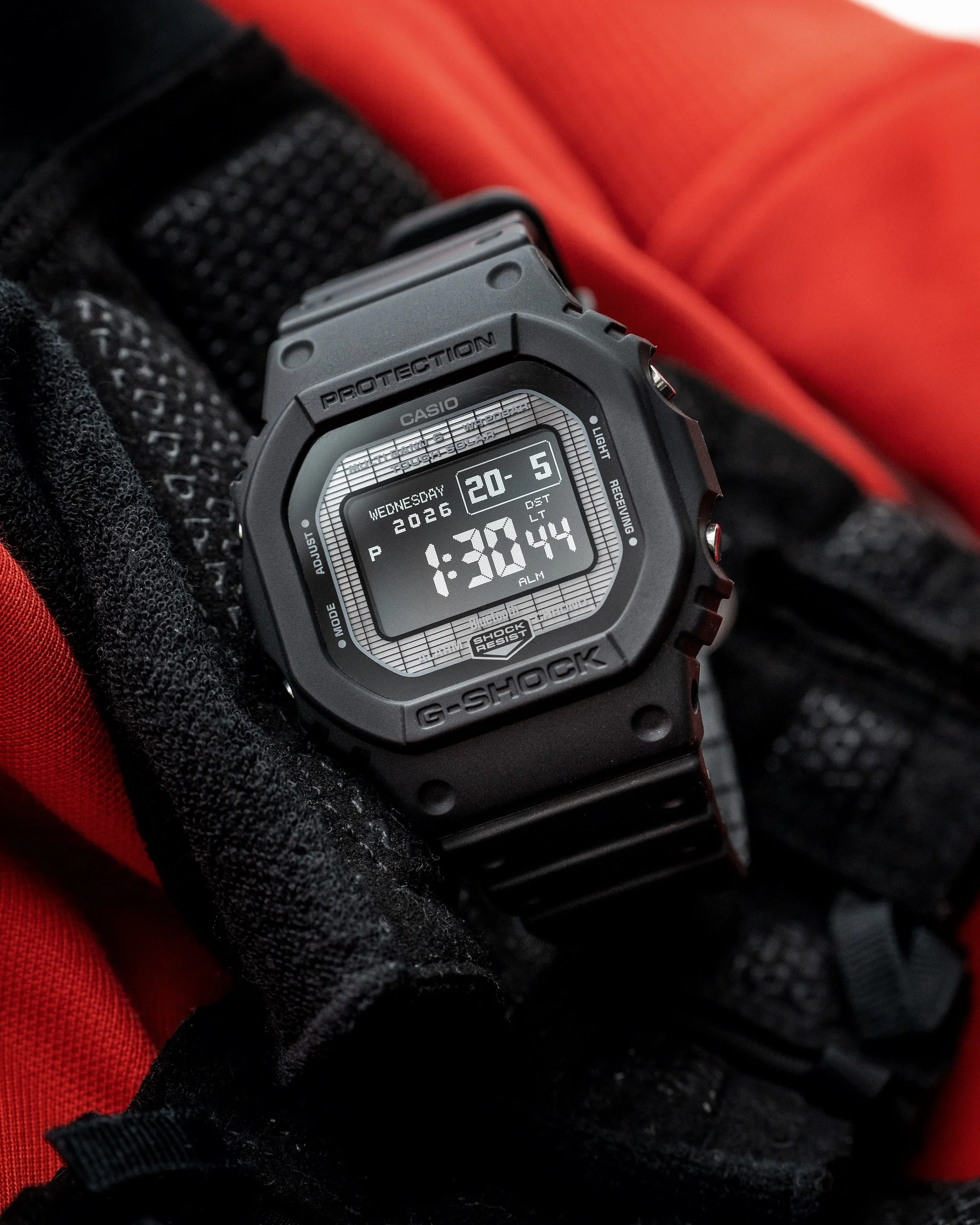 G-SHOCK GW-BX5600-1A1 black resin square case with negative MIP display against a red and black background