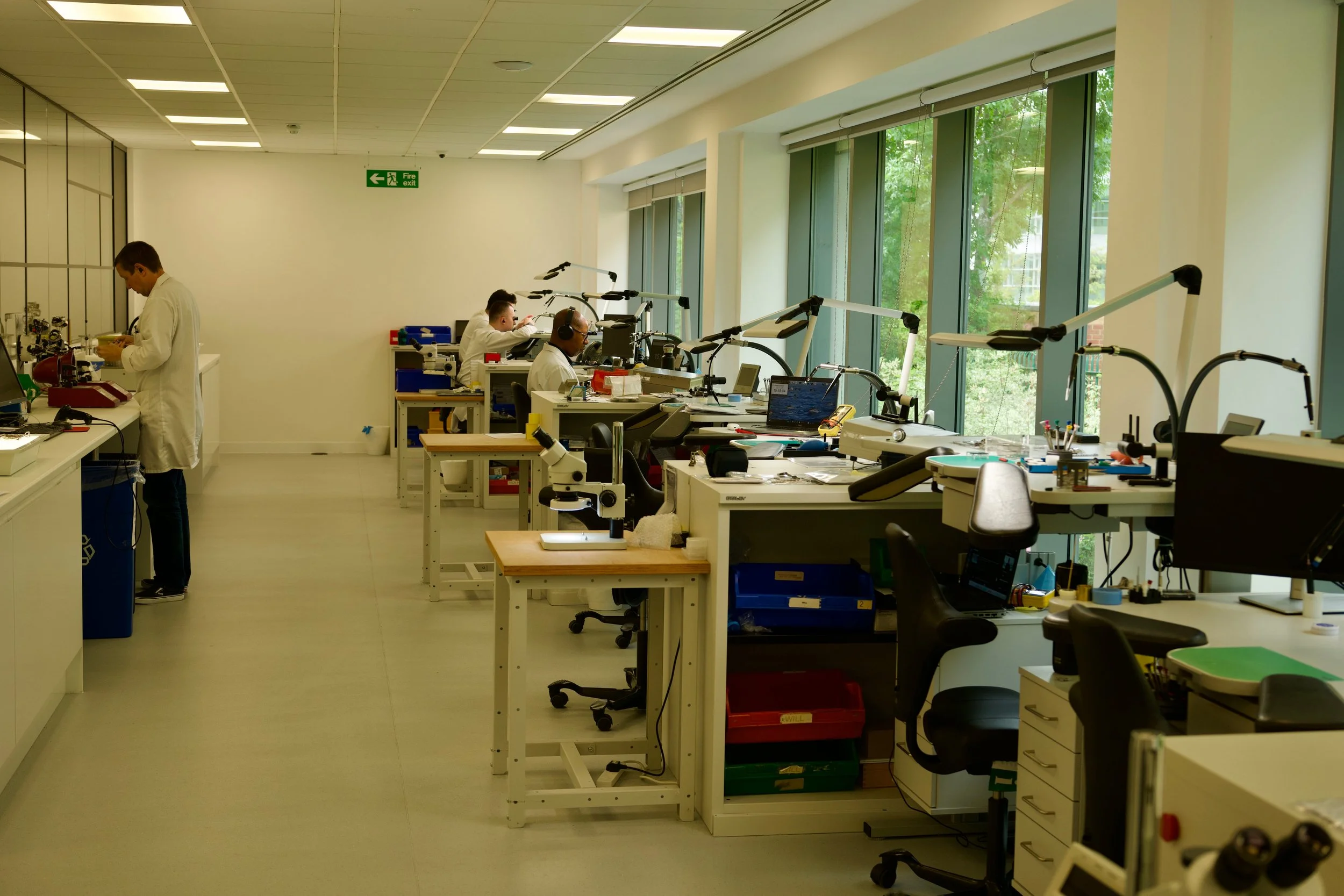 Watchmakers working at benches inside the Grand Seiko UK service centre workshop.