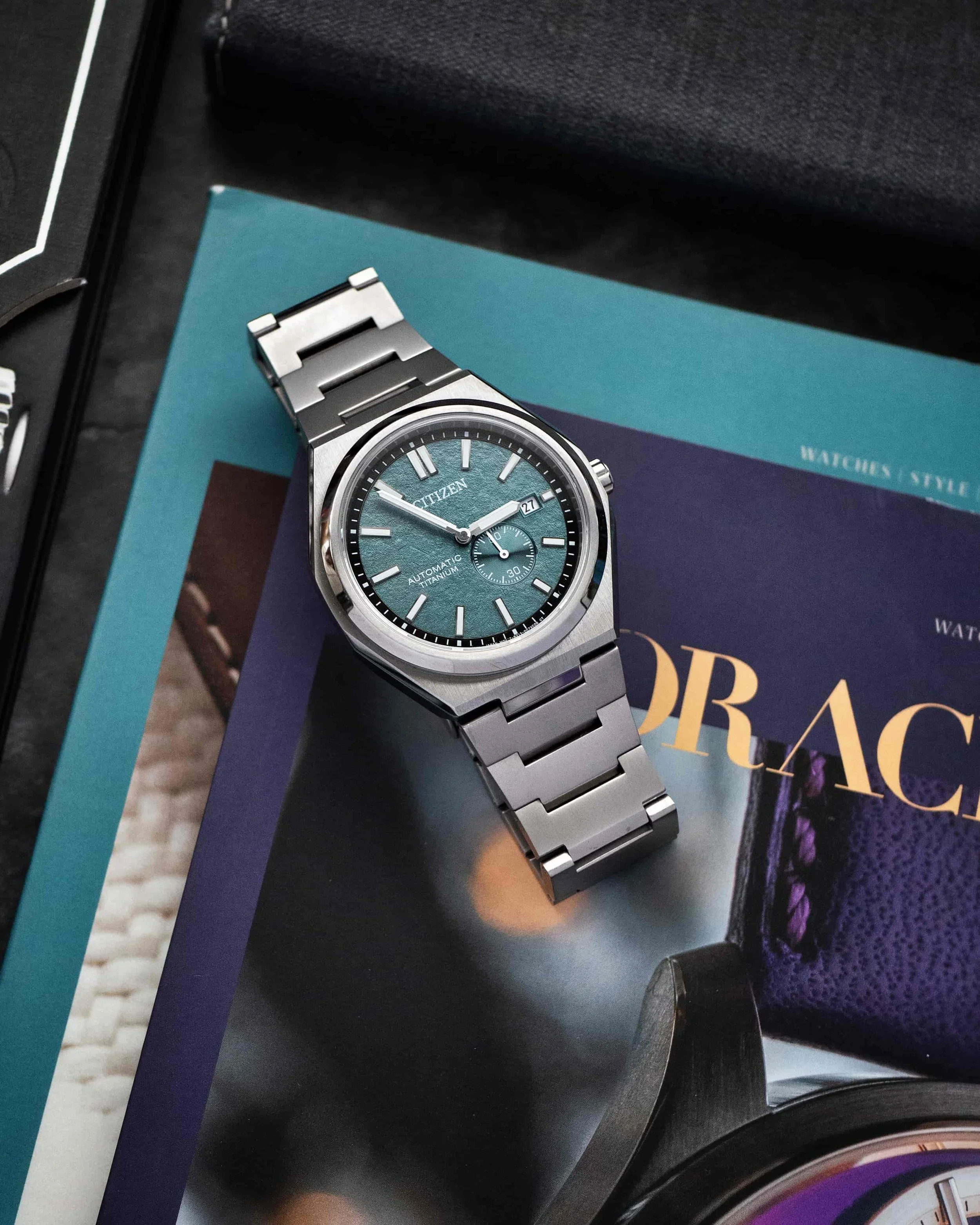 Citizen Zenshin NJ0180-80X Super Titanium with green textured dial in a flatlay scene.