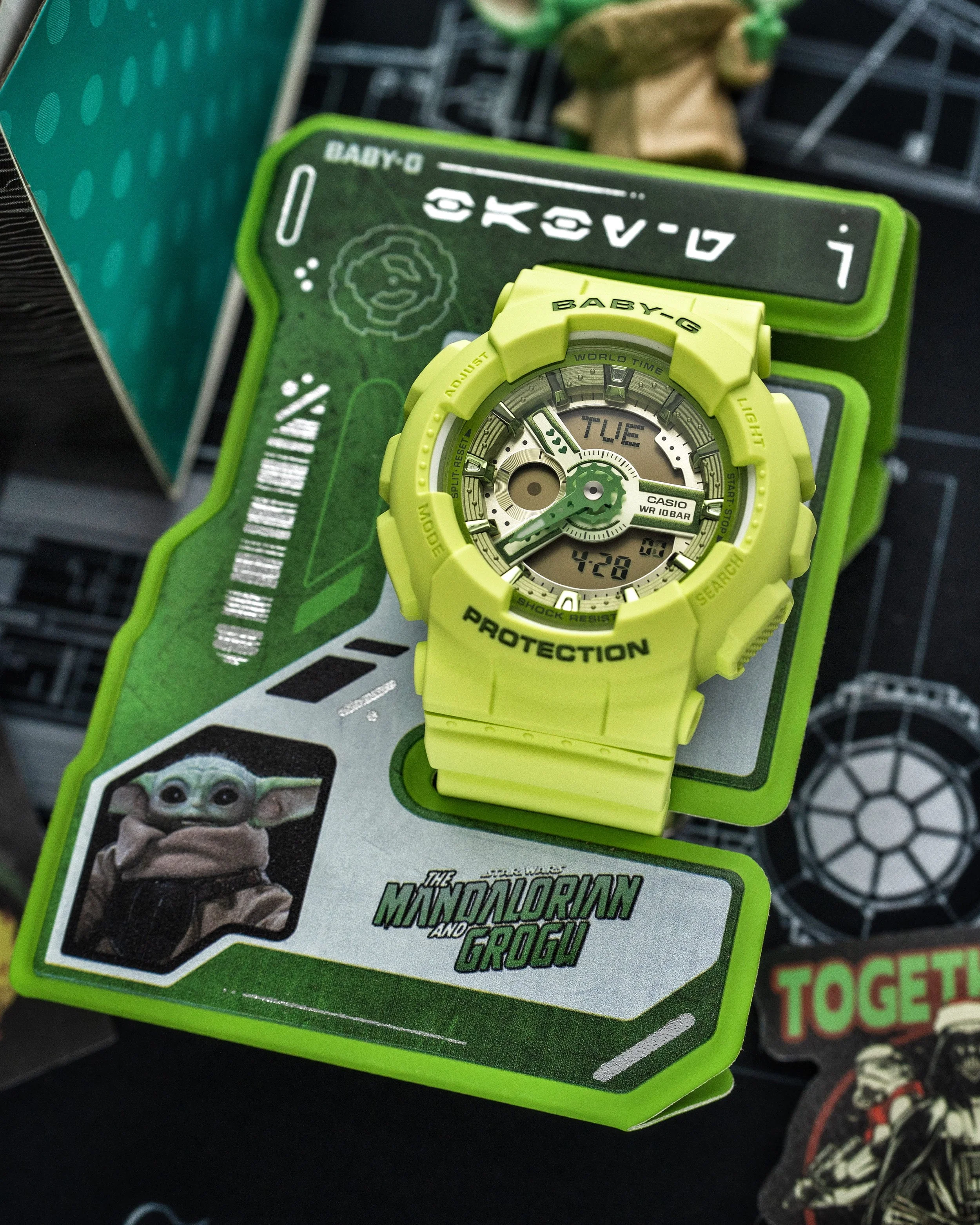 Baby-G BA-110 Grogu watch in vivid green with layered dial displayed on its Mandalorian and Grogu ID stand