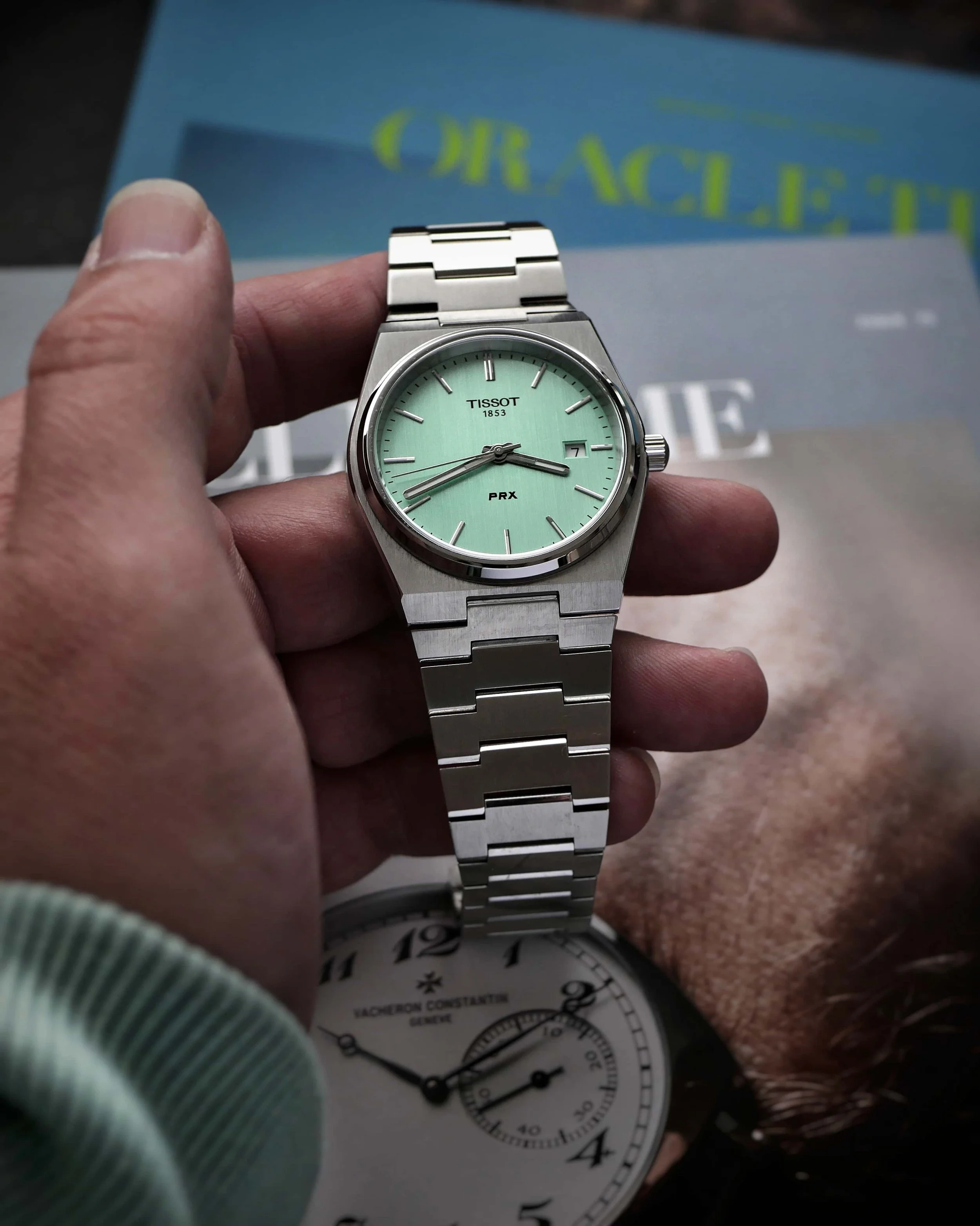 Mint-green Tissot PRX Quartz held in hand on its stainless-steel bracelet.