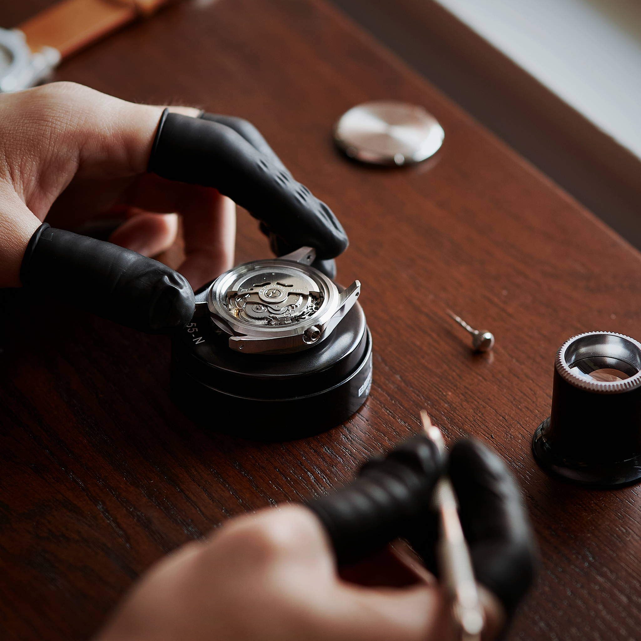 Open watch case showing the movement with the crown and stem beside it