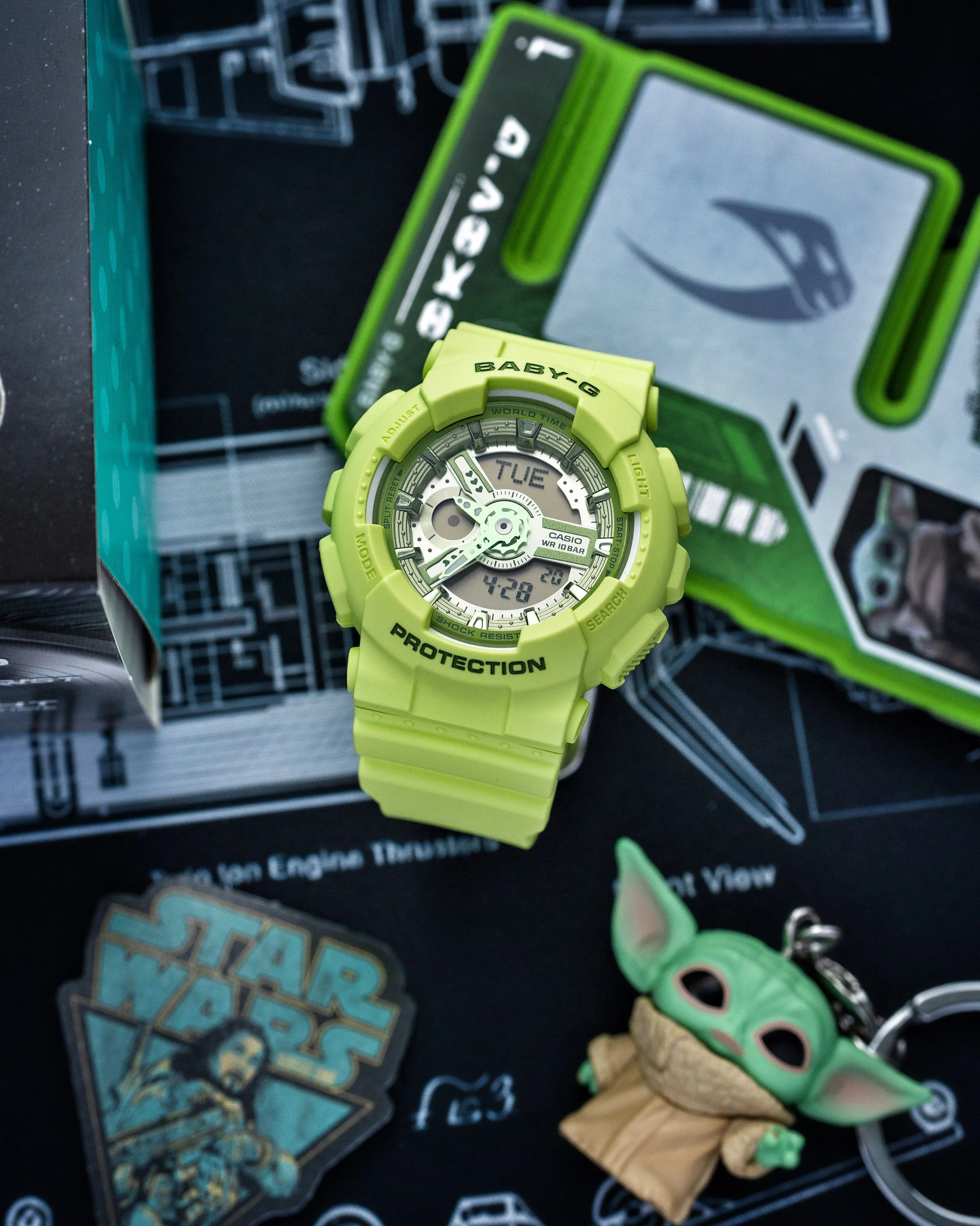 Baby-G BA-110 Grogu watch in vivid green photographed with Star Wars themed packaging and Grogu accessory