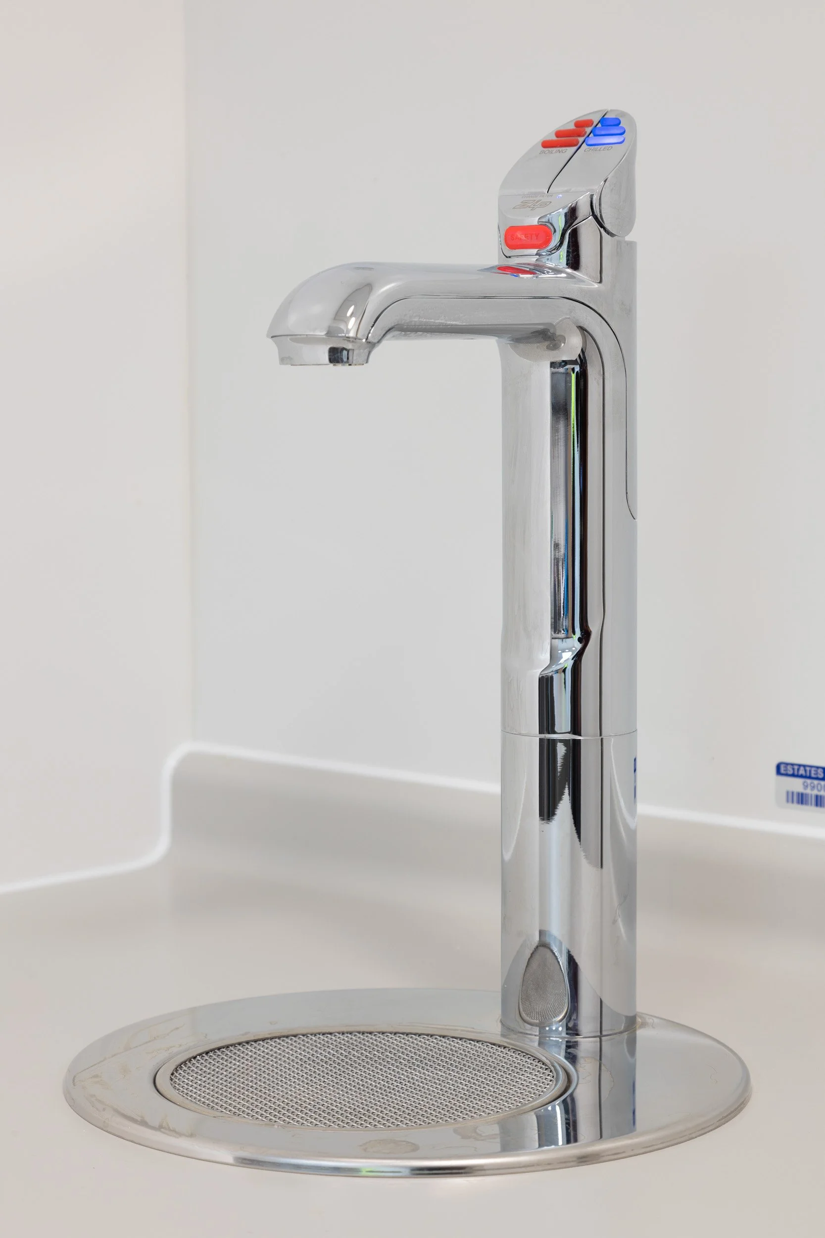 A modern, chrome-finished, touchless faucet with red and blue water temperature indicators mounted on a white sink countertop.