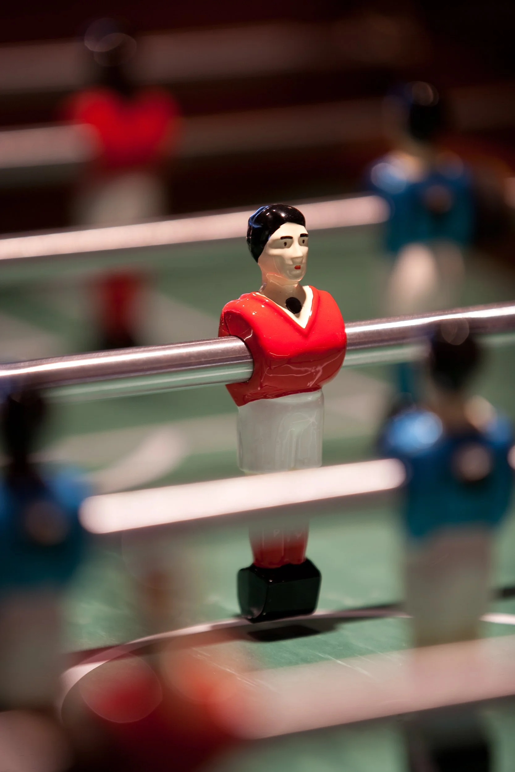 Foosball table with a close-up of a red player figurine.
