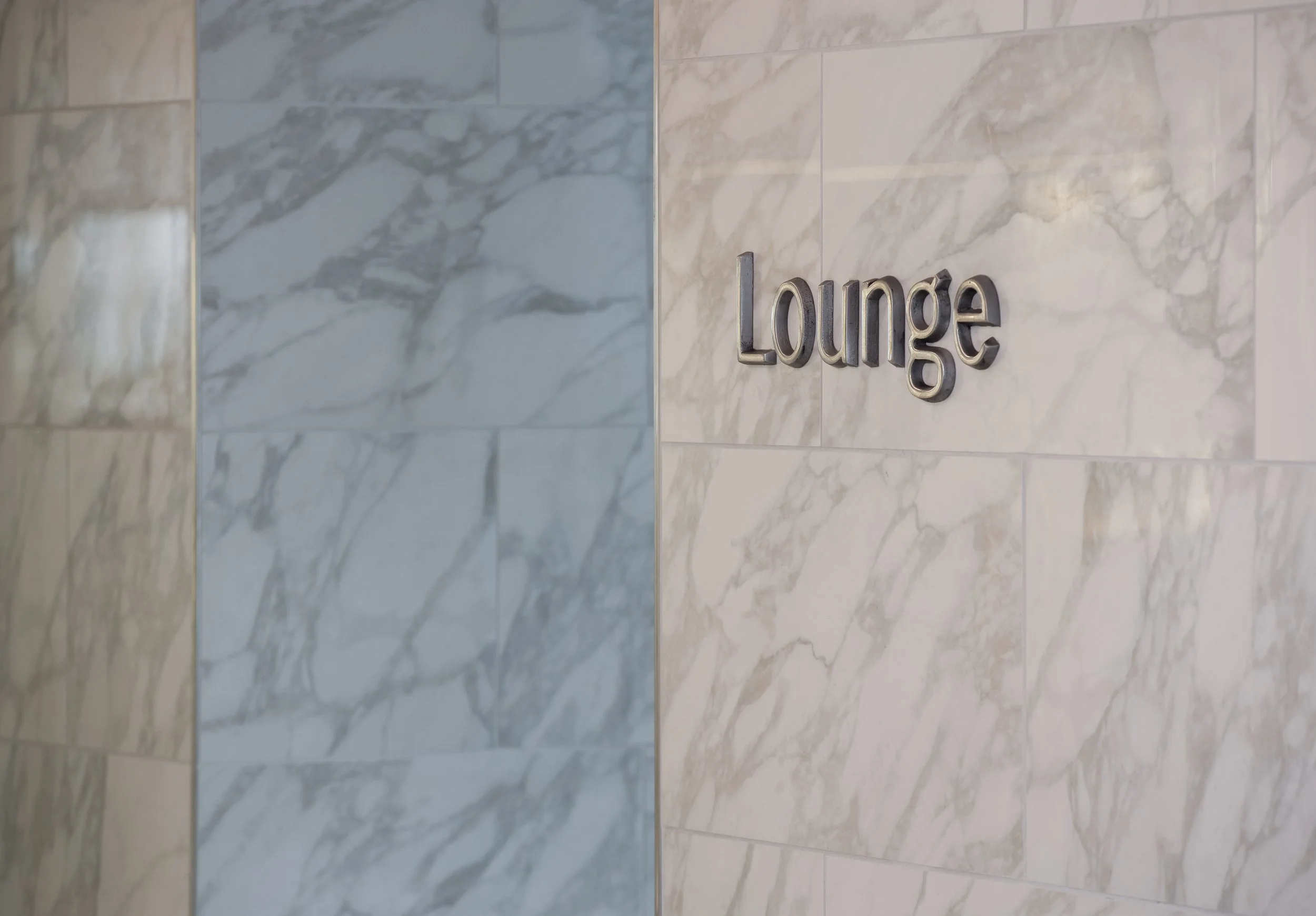 Wall with marble tiles and a sign that says 'Lounge'